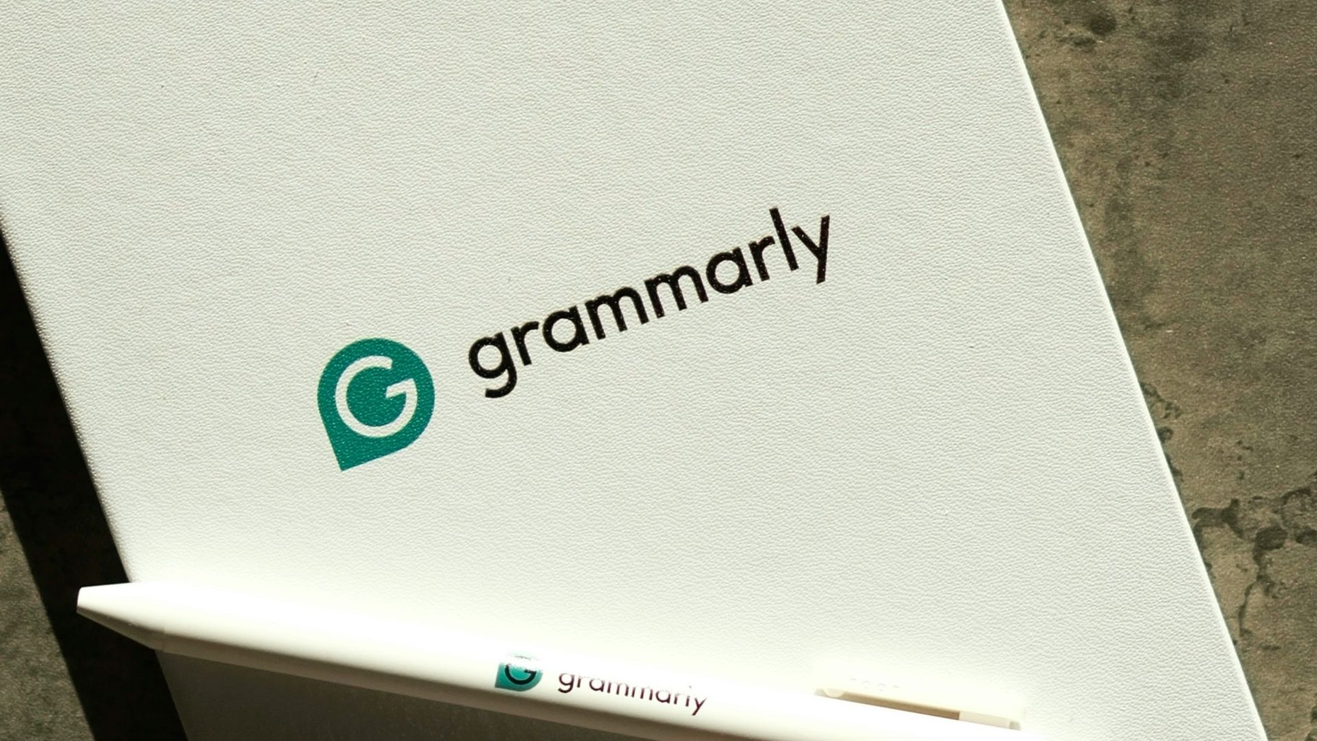 Grammarly notebook, pen, and keyboard on a desk.