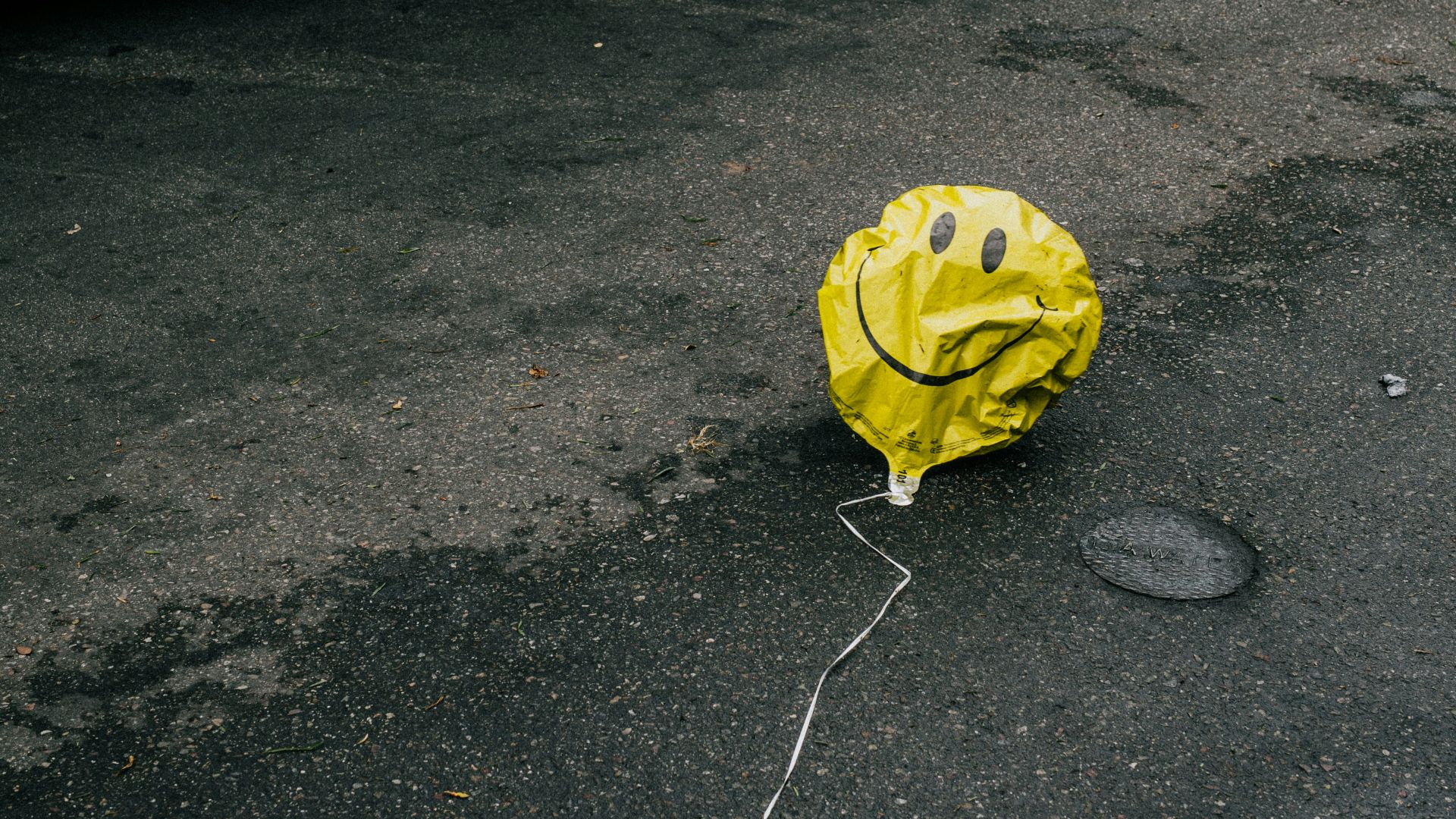 smiling emoji balloon beside black car during daytime
