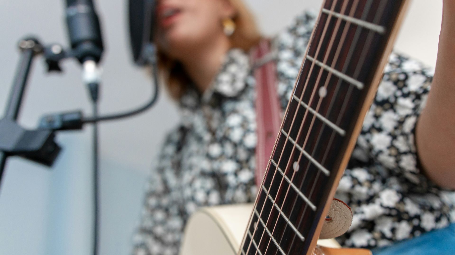 woman playing acoustic guitar while singing using condenser microphone
