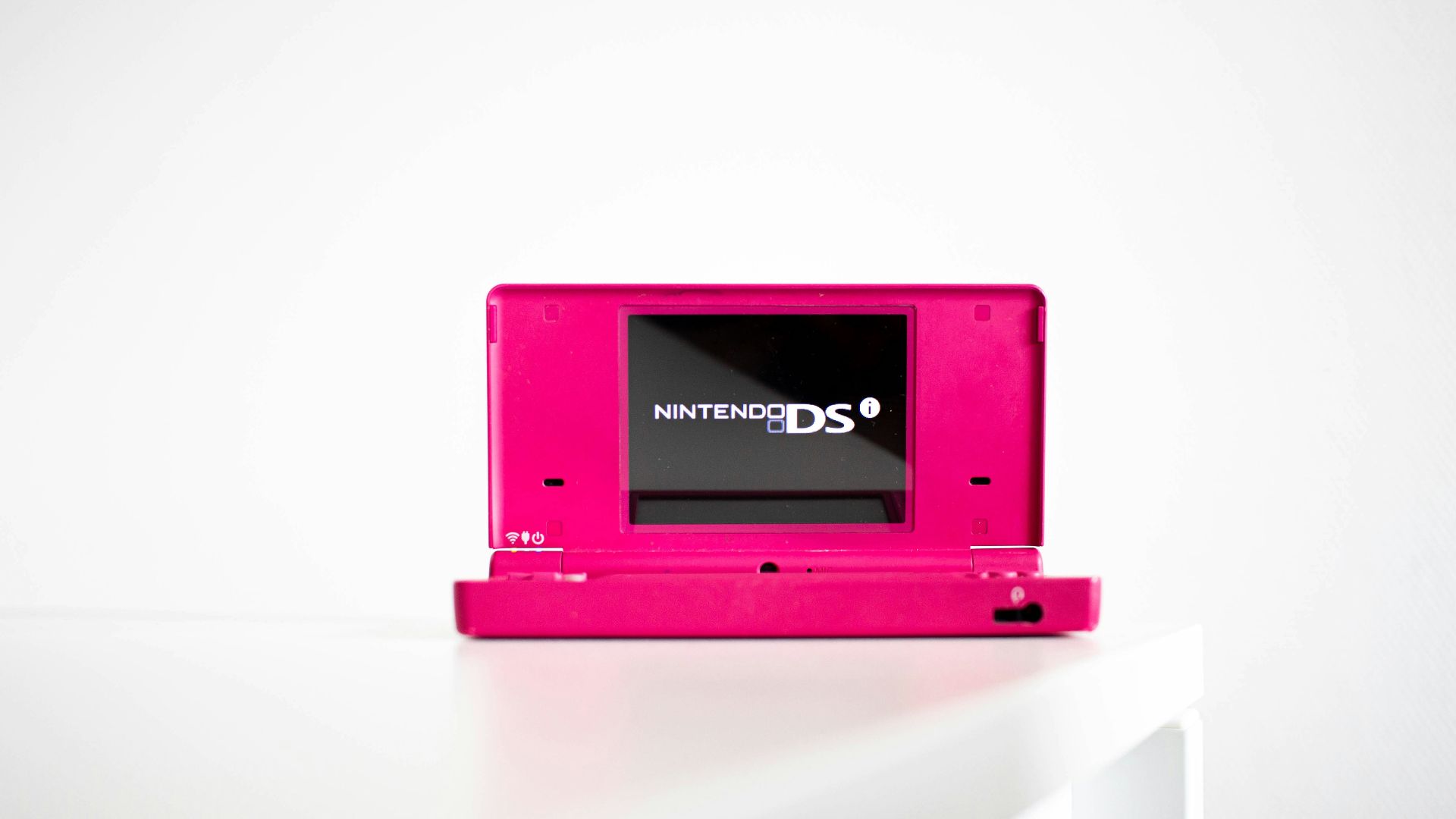 a pink nintendo ds sitting on top of a white table