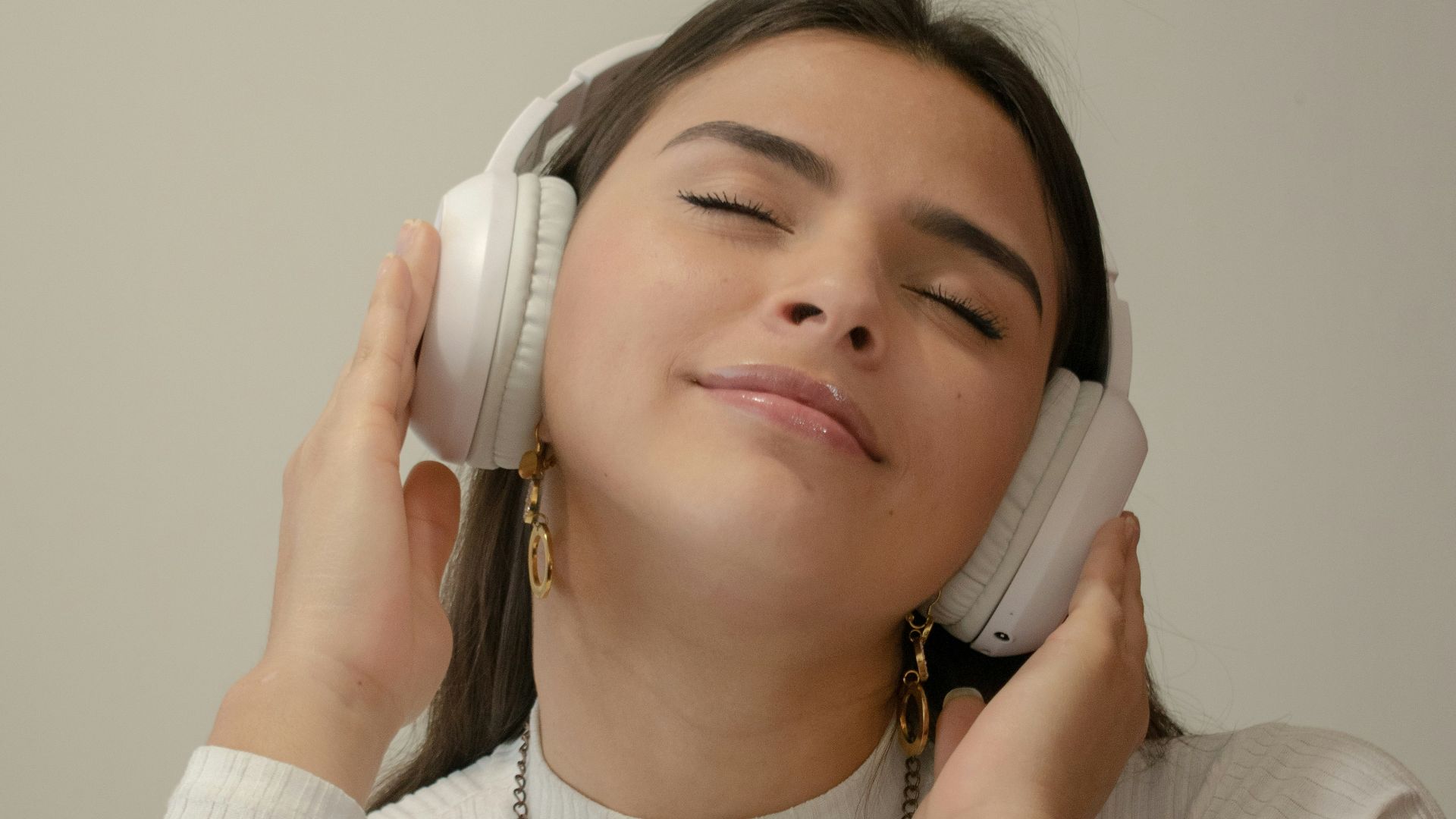 a woman with her eyes closed holding a phone to her ear