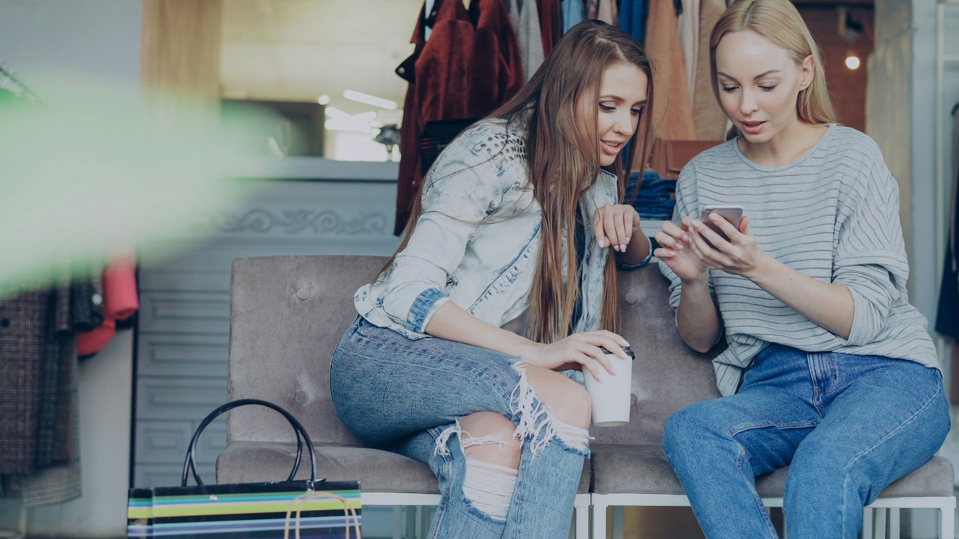 Two women are looking at a phone in a store.