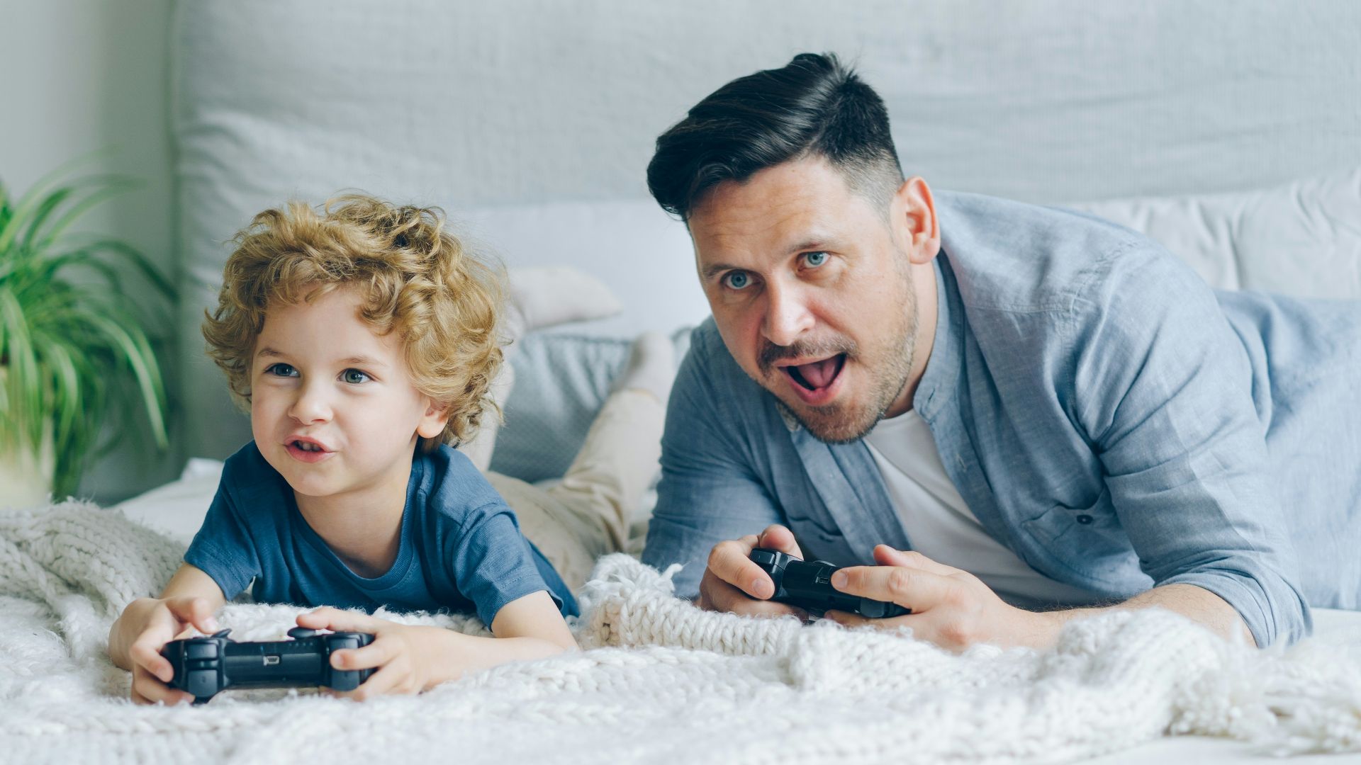 a man and a child laying on a bed playing a video game