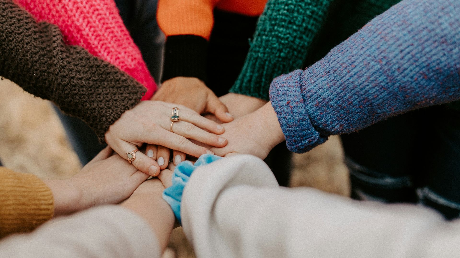 person in red sweater holding babys hand
