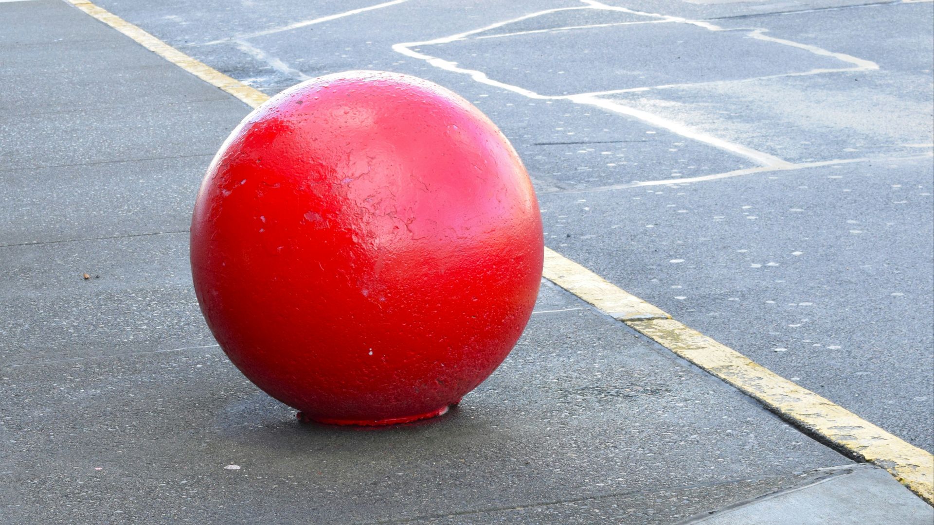 a large red ball sitting on the side of a road