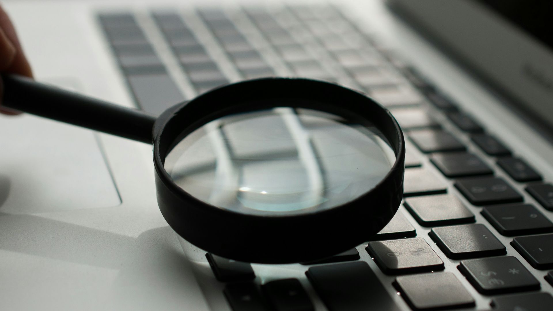 magnifying glass near gray laptop computer
