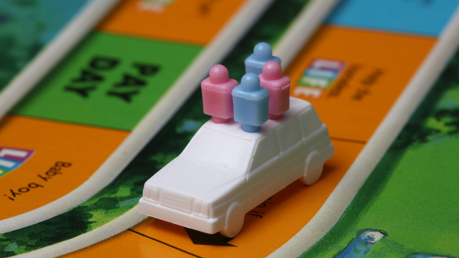 white and blue car toy on top of orange game board