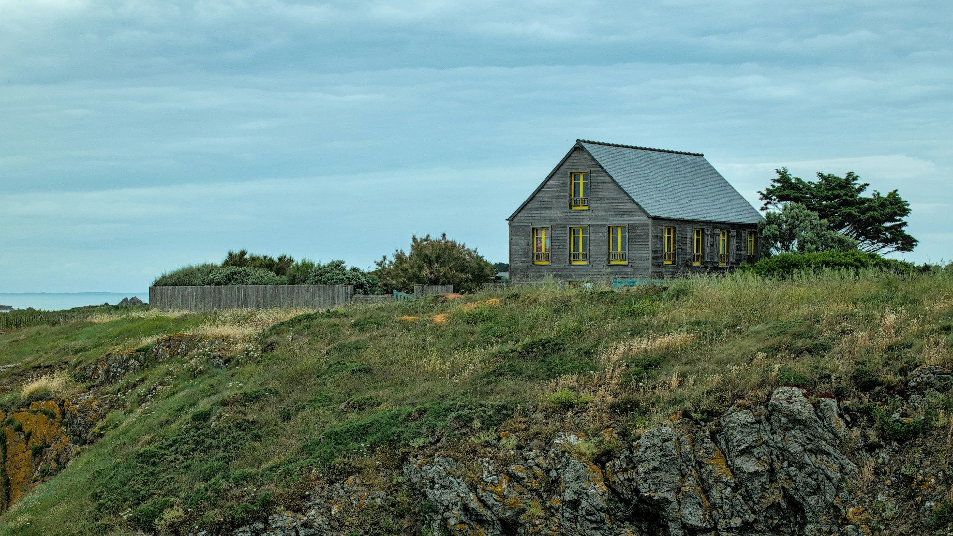 A solitary house sits atop a craggy cliff.