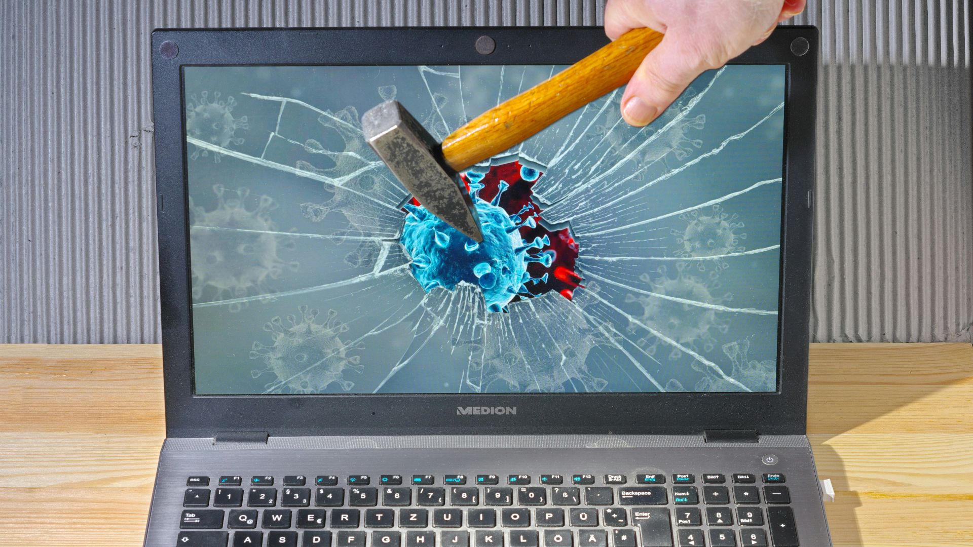 a person holding a pencil and a broken laptop