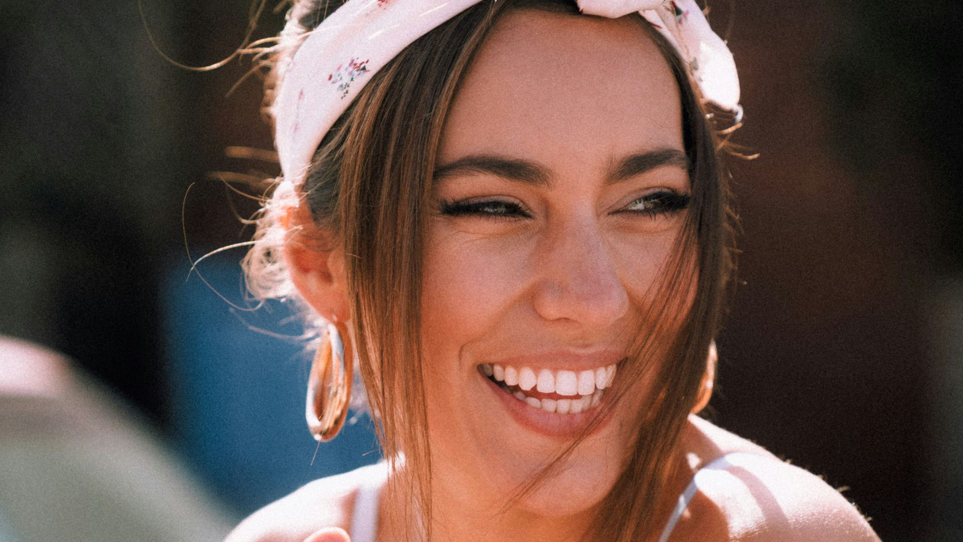 smiling woman in white tank top holding black smartphone