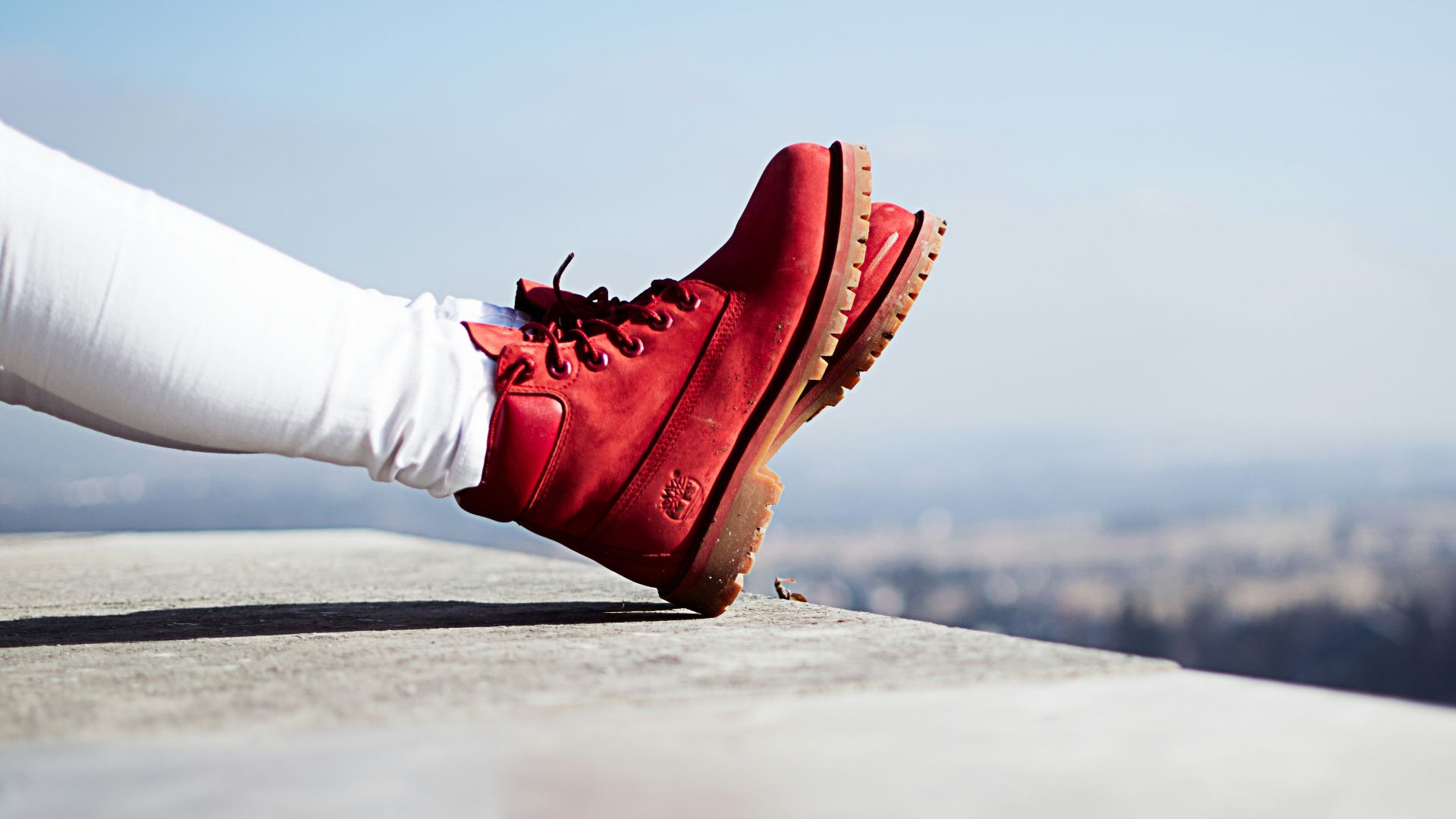 person wearing pair of red boots sitting on building top