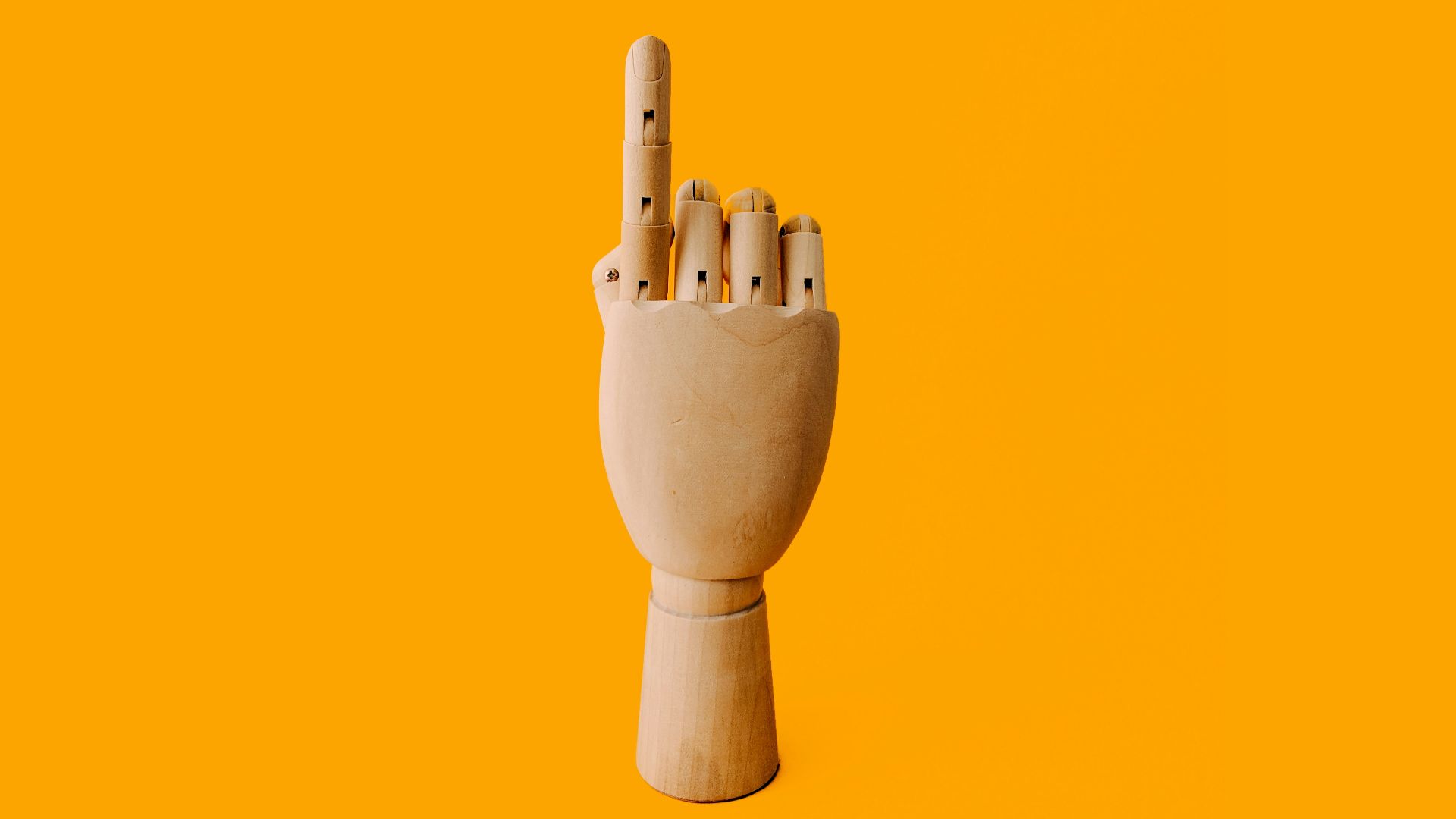 beige wooden hand sculpture with orange background