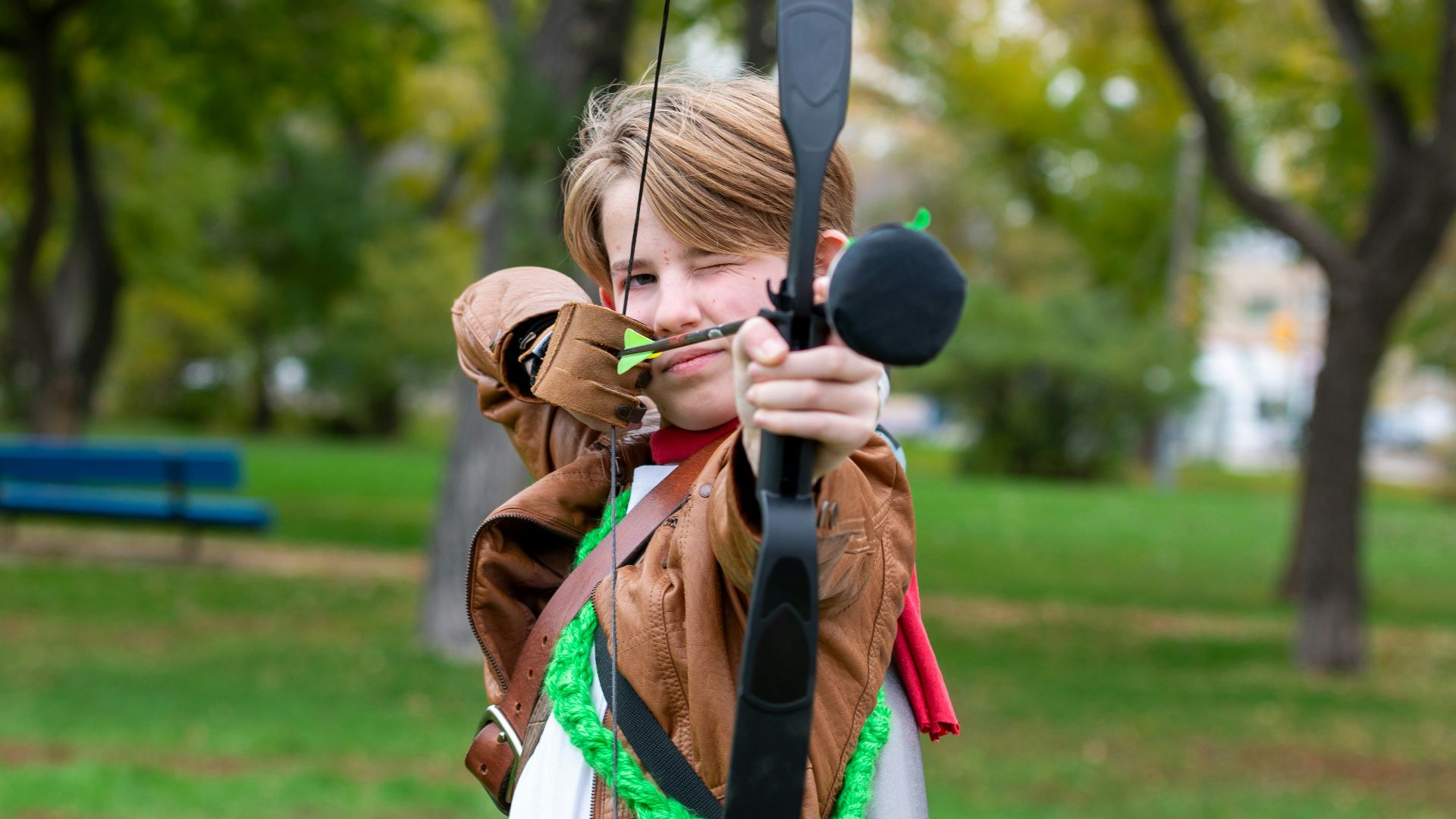 a woman holding a bow and arrow in a park