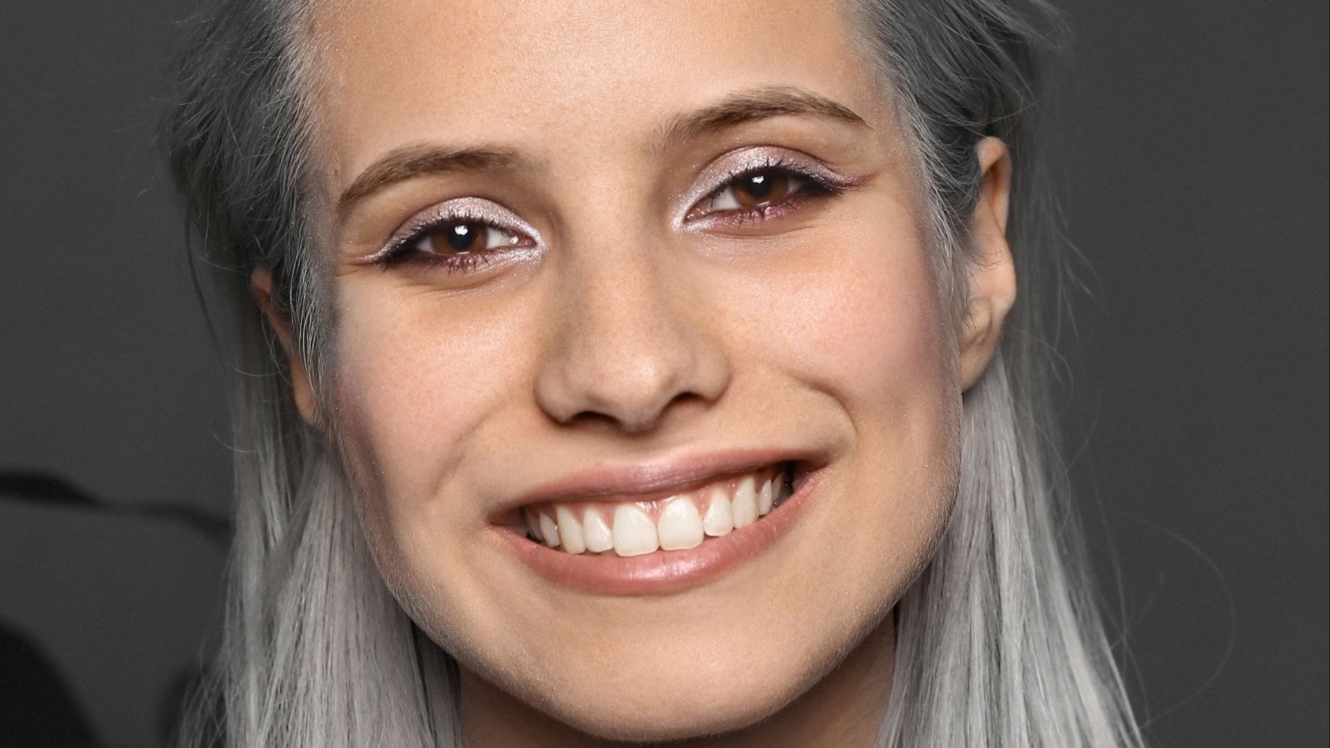 a woman with grey hair smiling at the camera