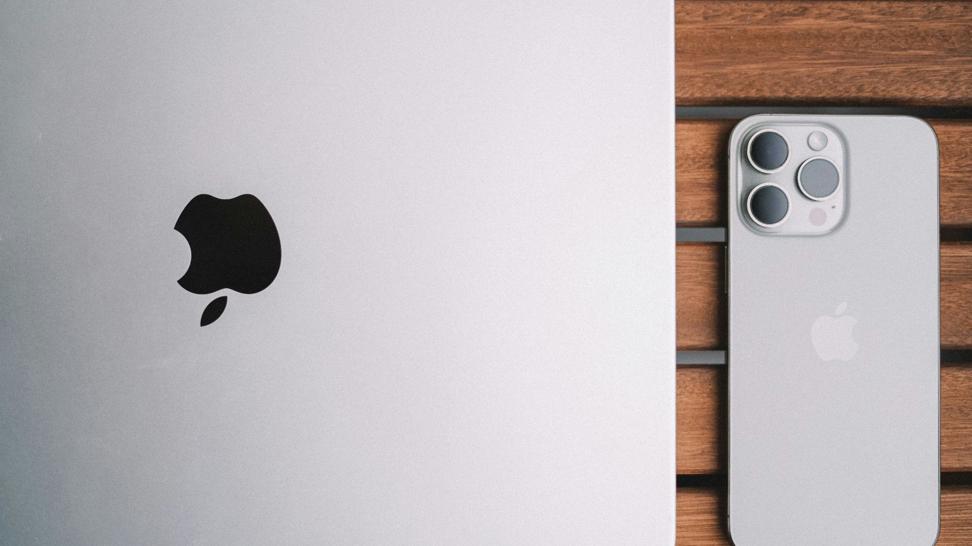 An apple laptop computer sitting on top of a wooden table