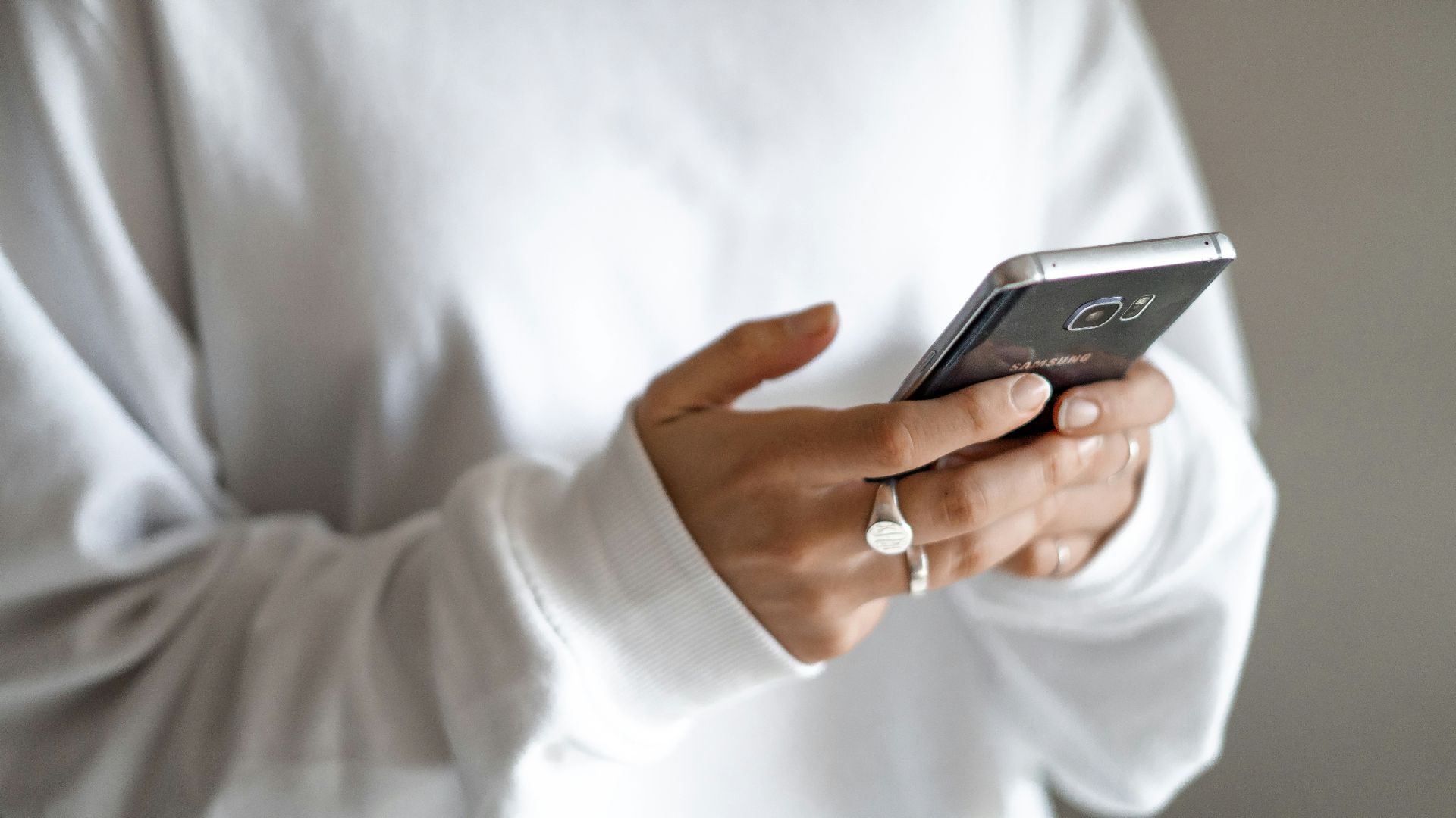 person in white long sleeve shirt holding black smartphone