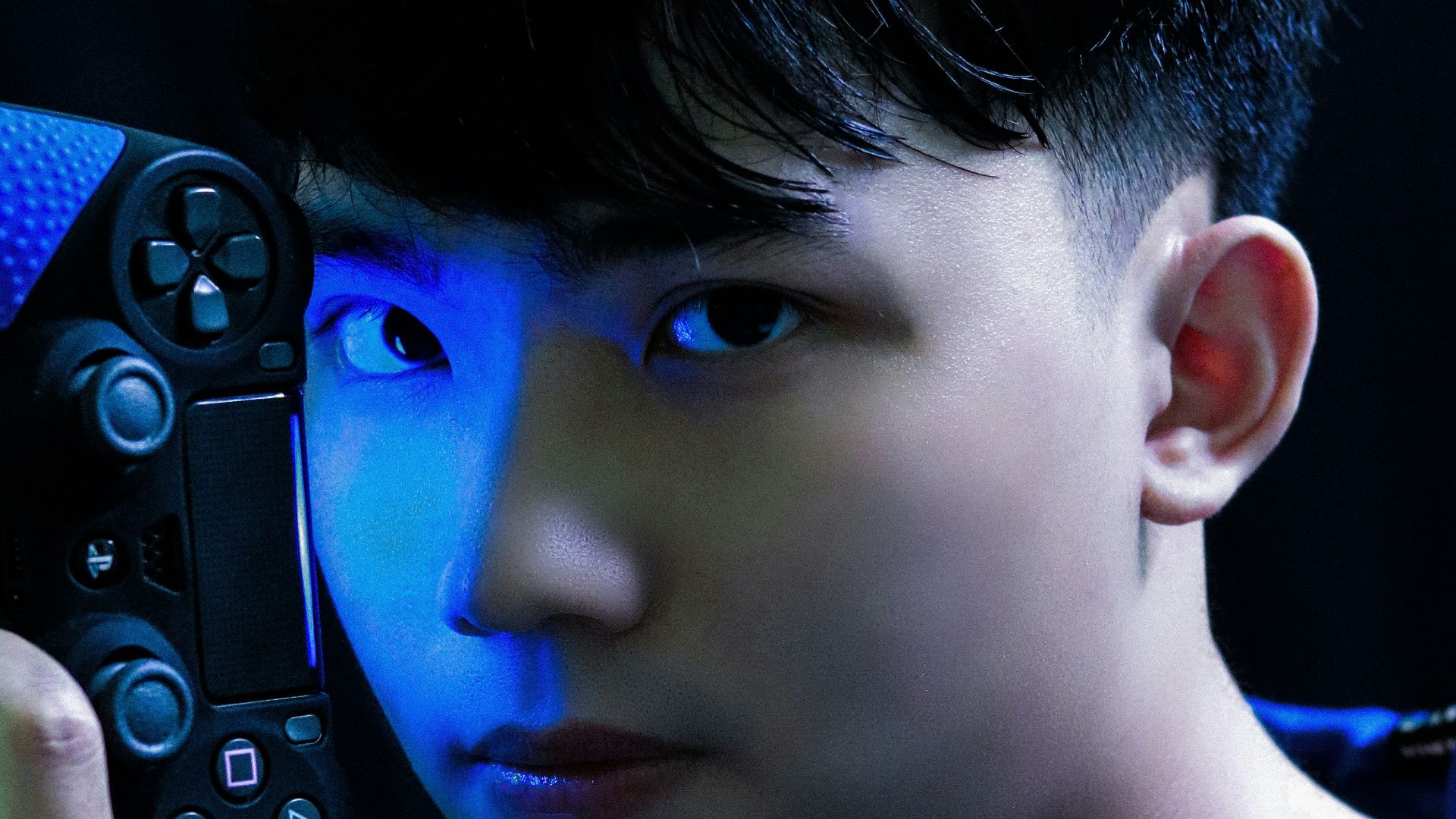 boy in blue long sleeve shirt holding black game controller