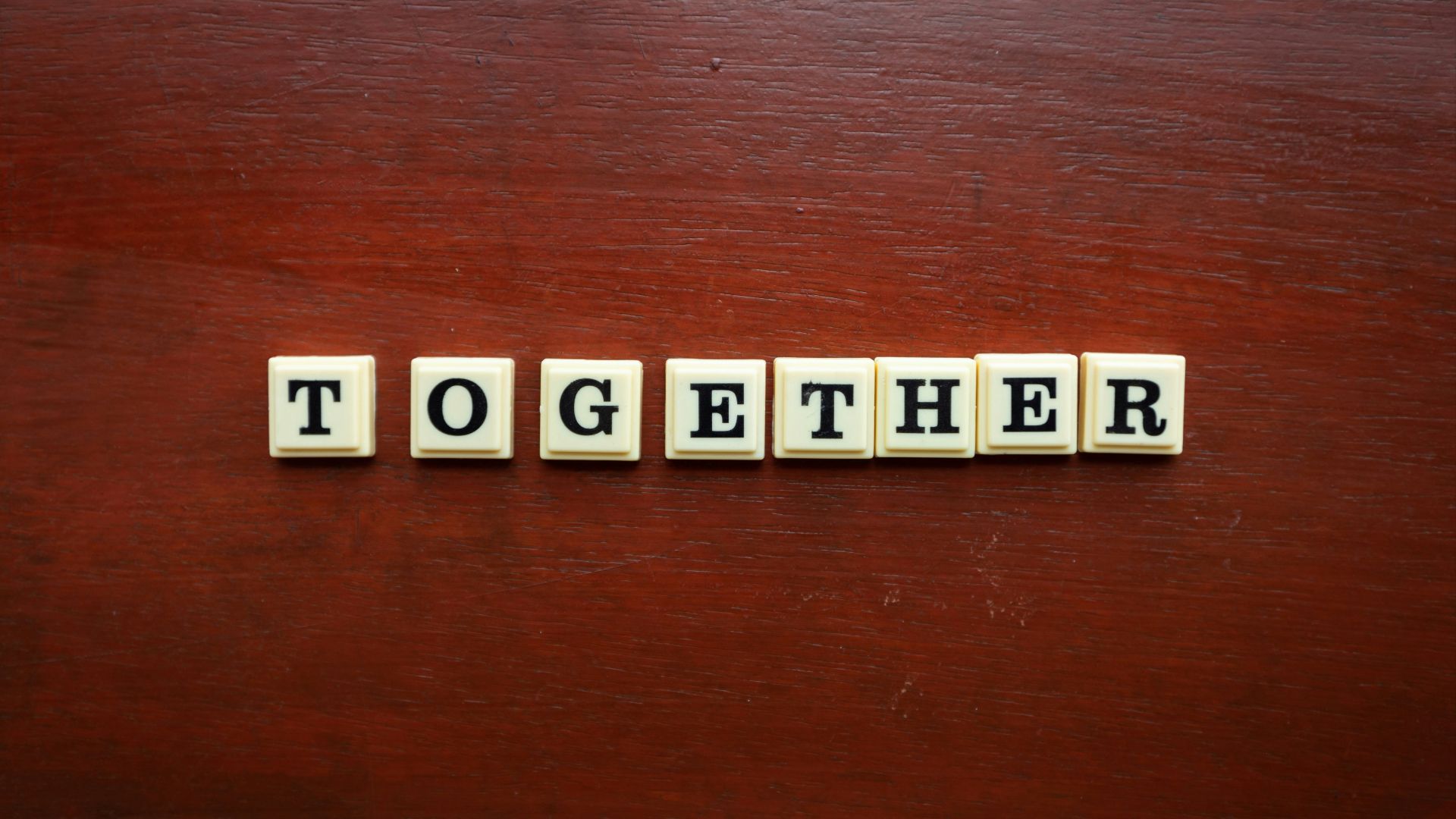 the word together spelled with scrabble tiles on a wooden surface