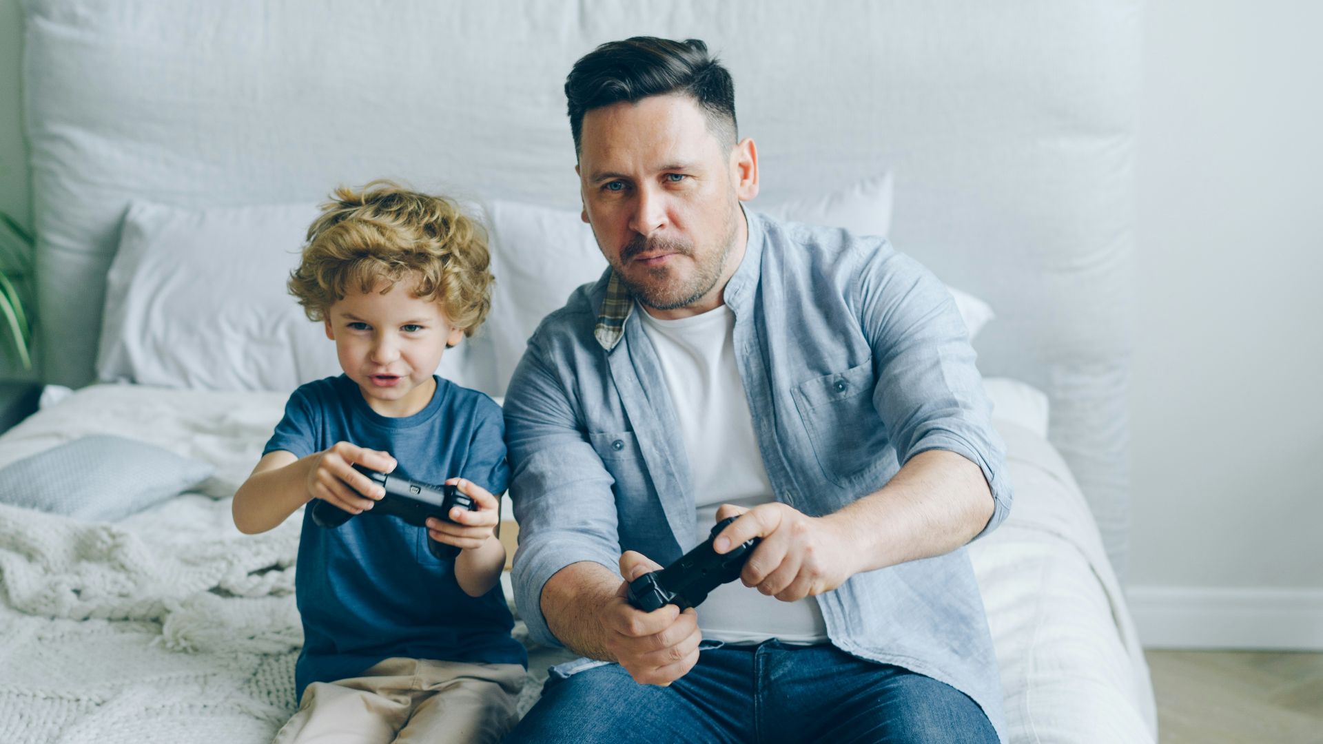 a man sitting on a bed next to a little boy