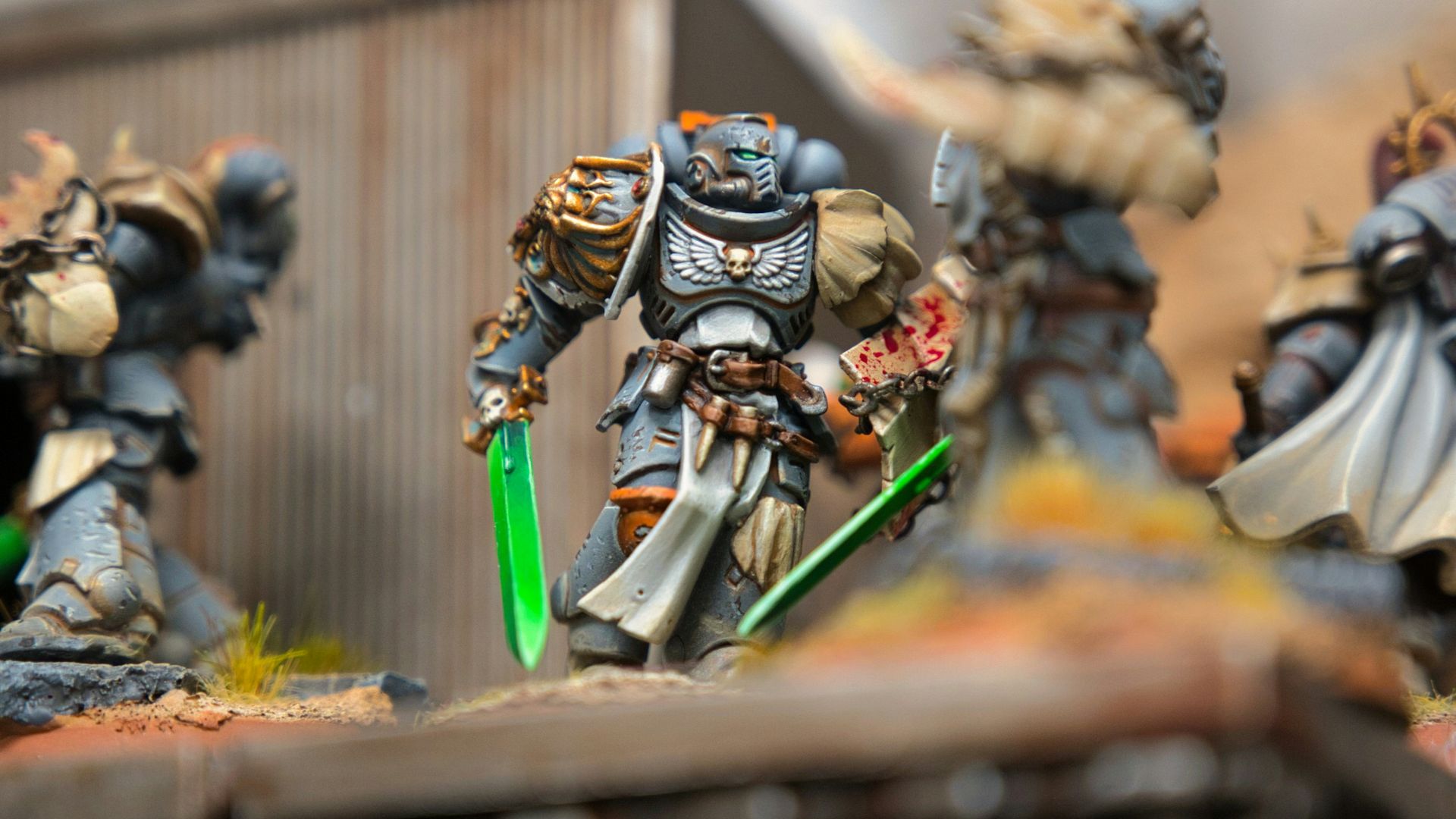 A group of warhammers on a table with a building in the background