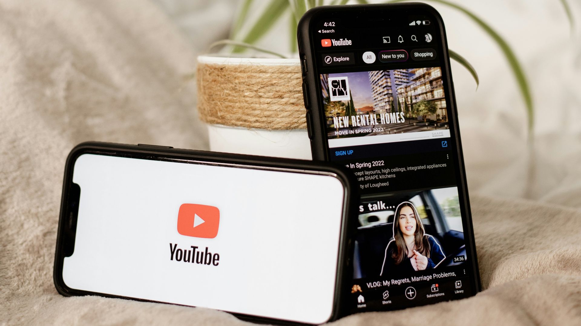 a cell phone sitting on top of a bed next to a plant