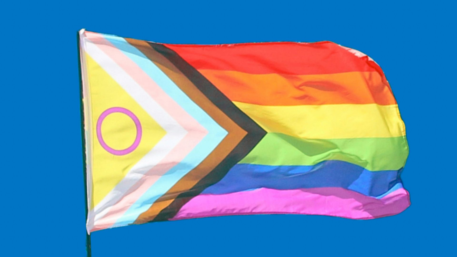 a rainbow colored kite flying in a blue sky