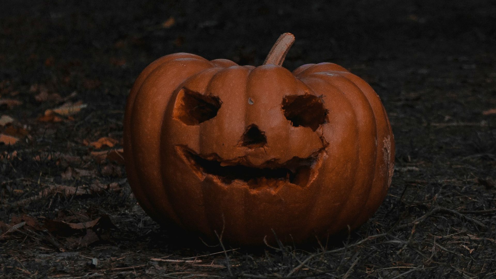 a carved pumpkin sitting in the middle of a field