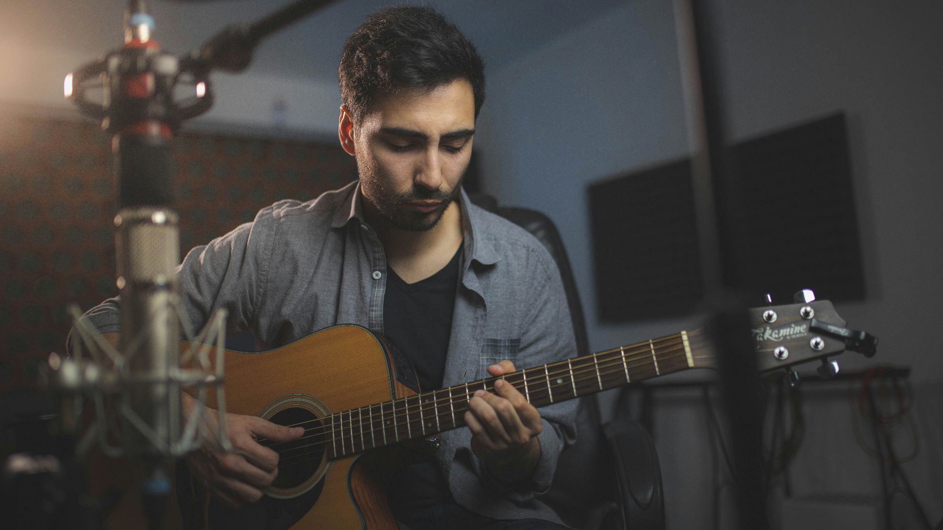 a man playing a guitar in a recording studio