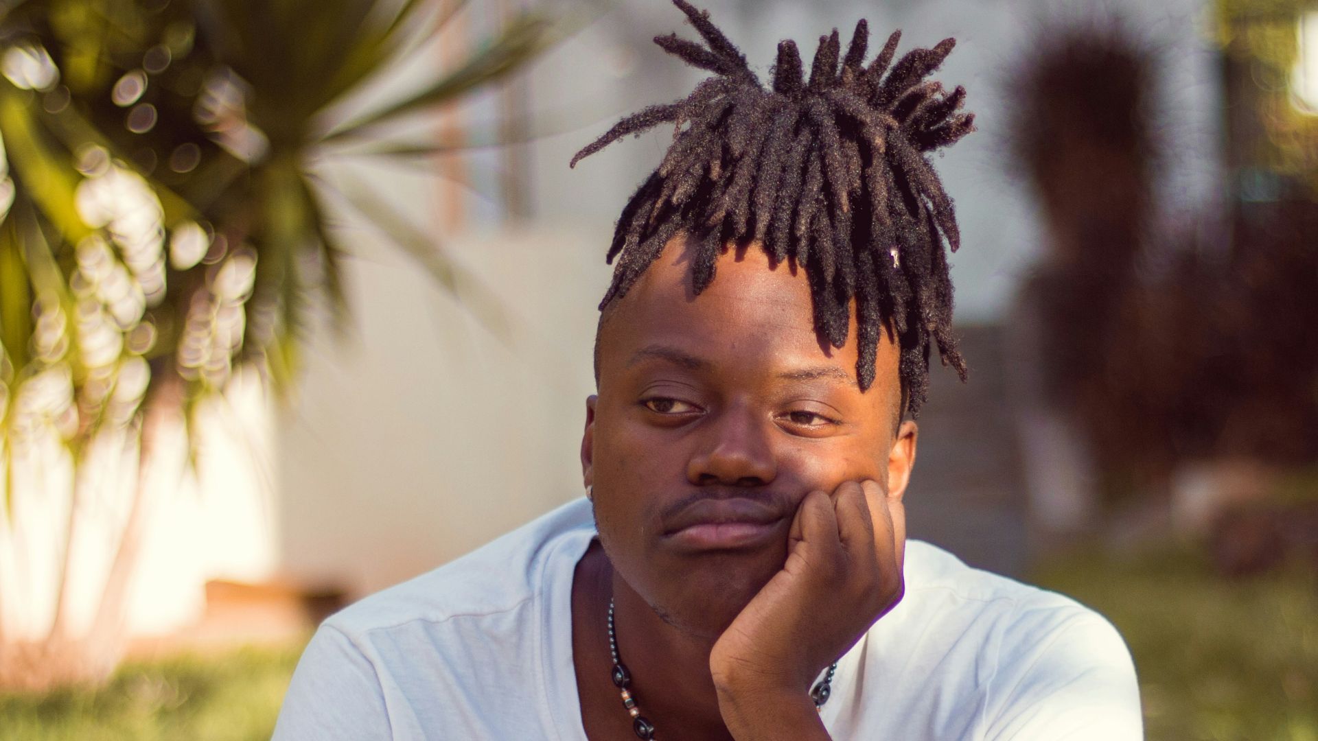 man in white crew neck t-shirt sitting on brown wooden chair