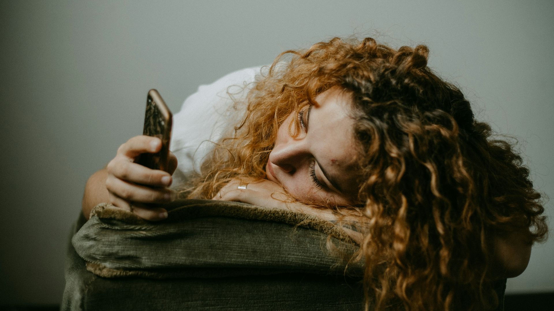 woman in gray sweater holding smartphone