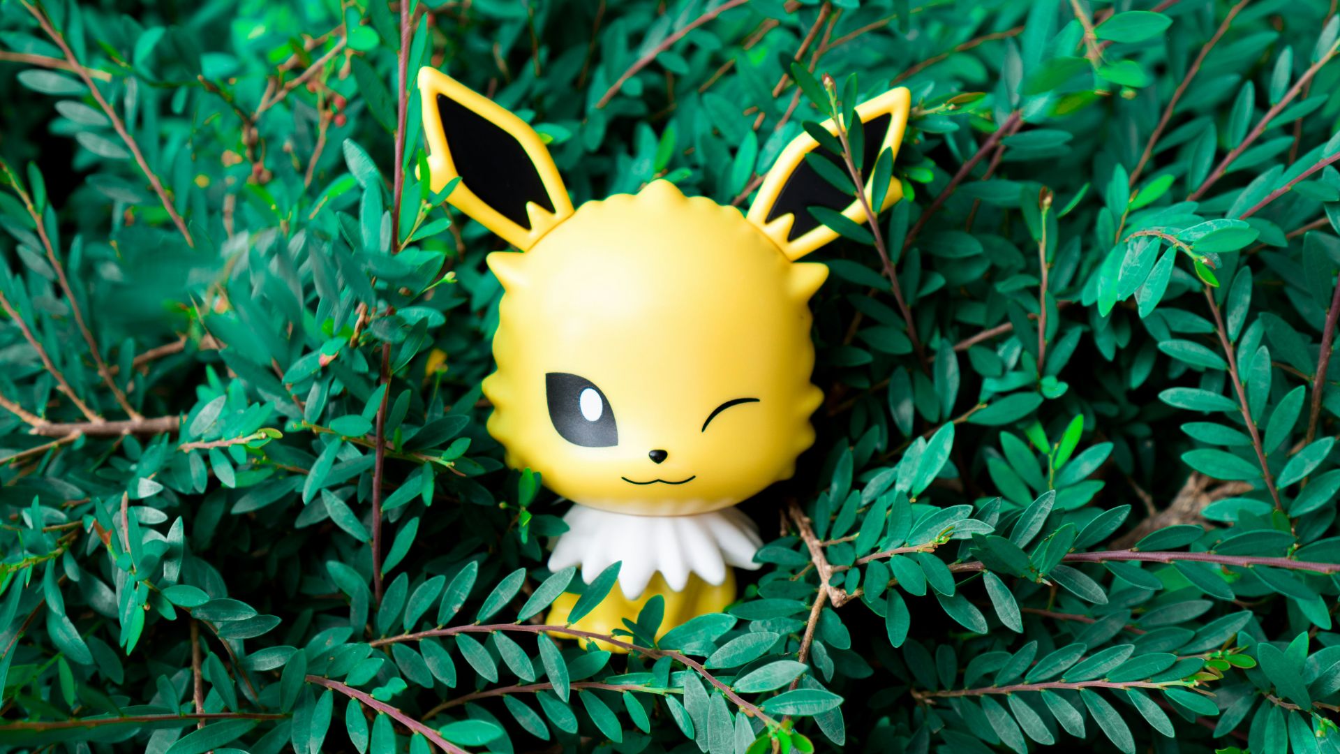 yellow smiley plush toy on green leaves