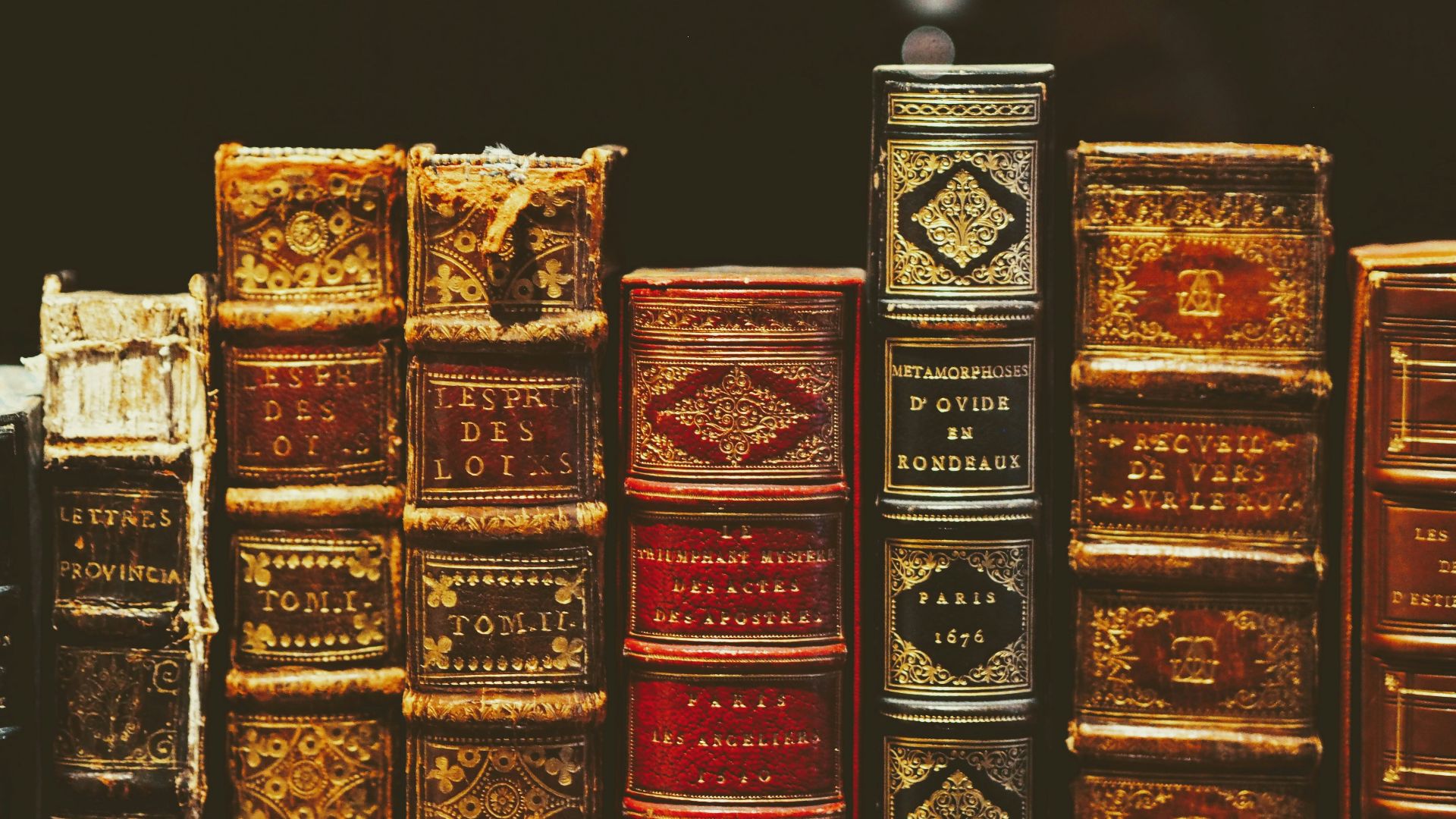 seven hardbound books on black surface