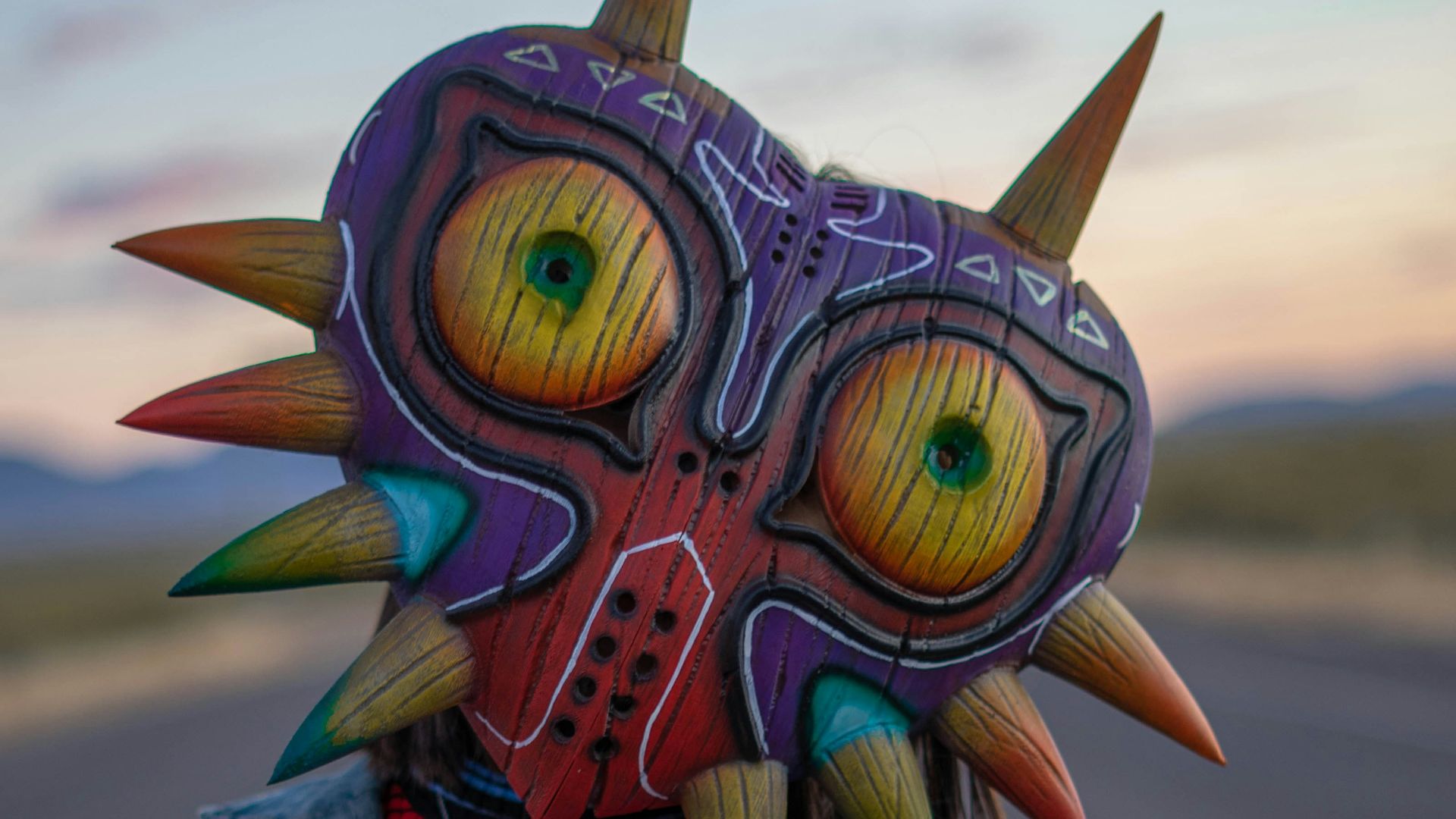 person in blue denim jacket with yellow green and blue owl mask