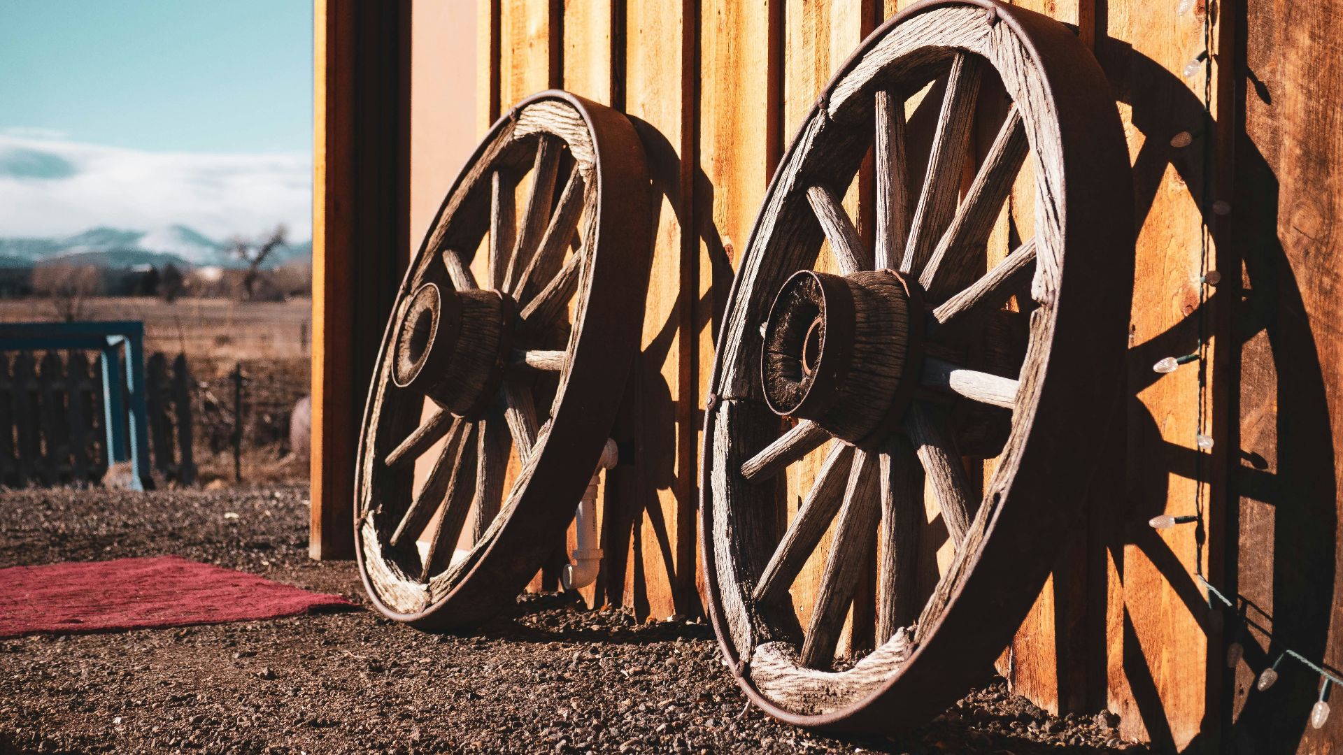 two brown carriage wheels learning on brown house