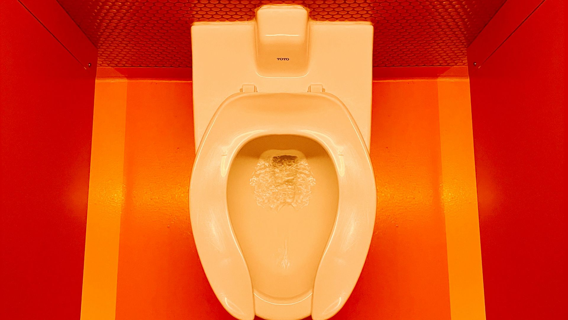 a white toilet sitting in a bathroom next to a red wall