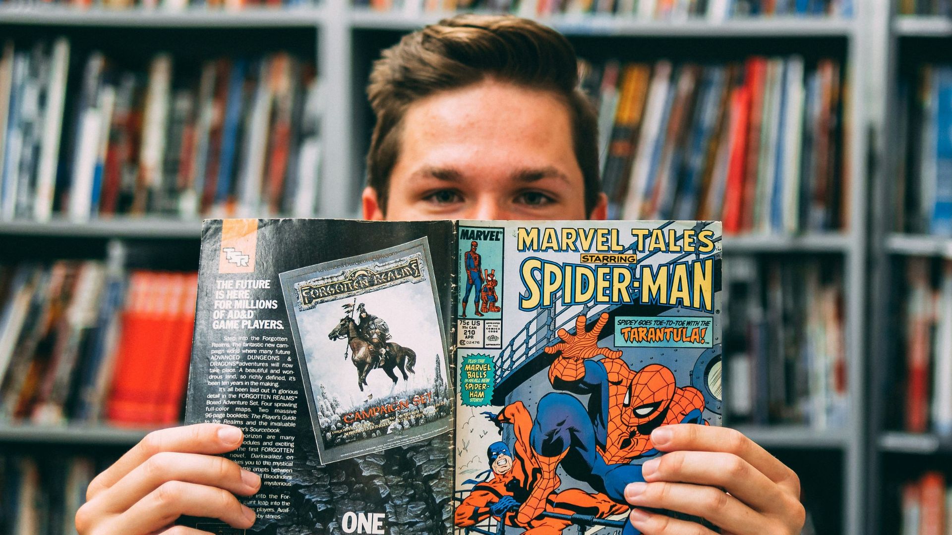 A man holding up a book in front of a library full of books