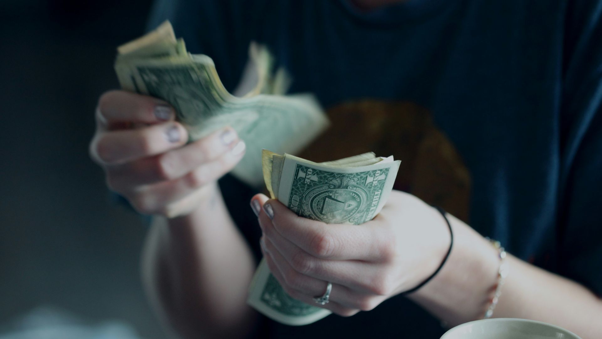 focus photography of person counting dollar banknotes
