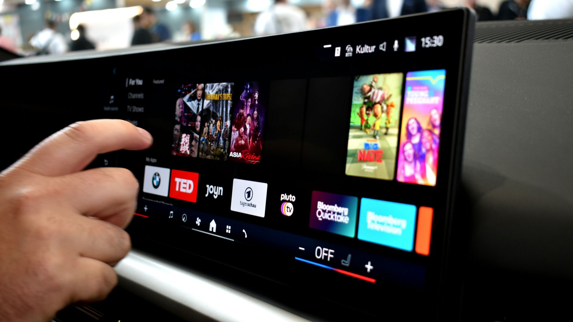 Person touching a car infotainment screen with media options.