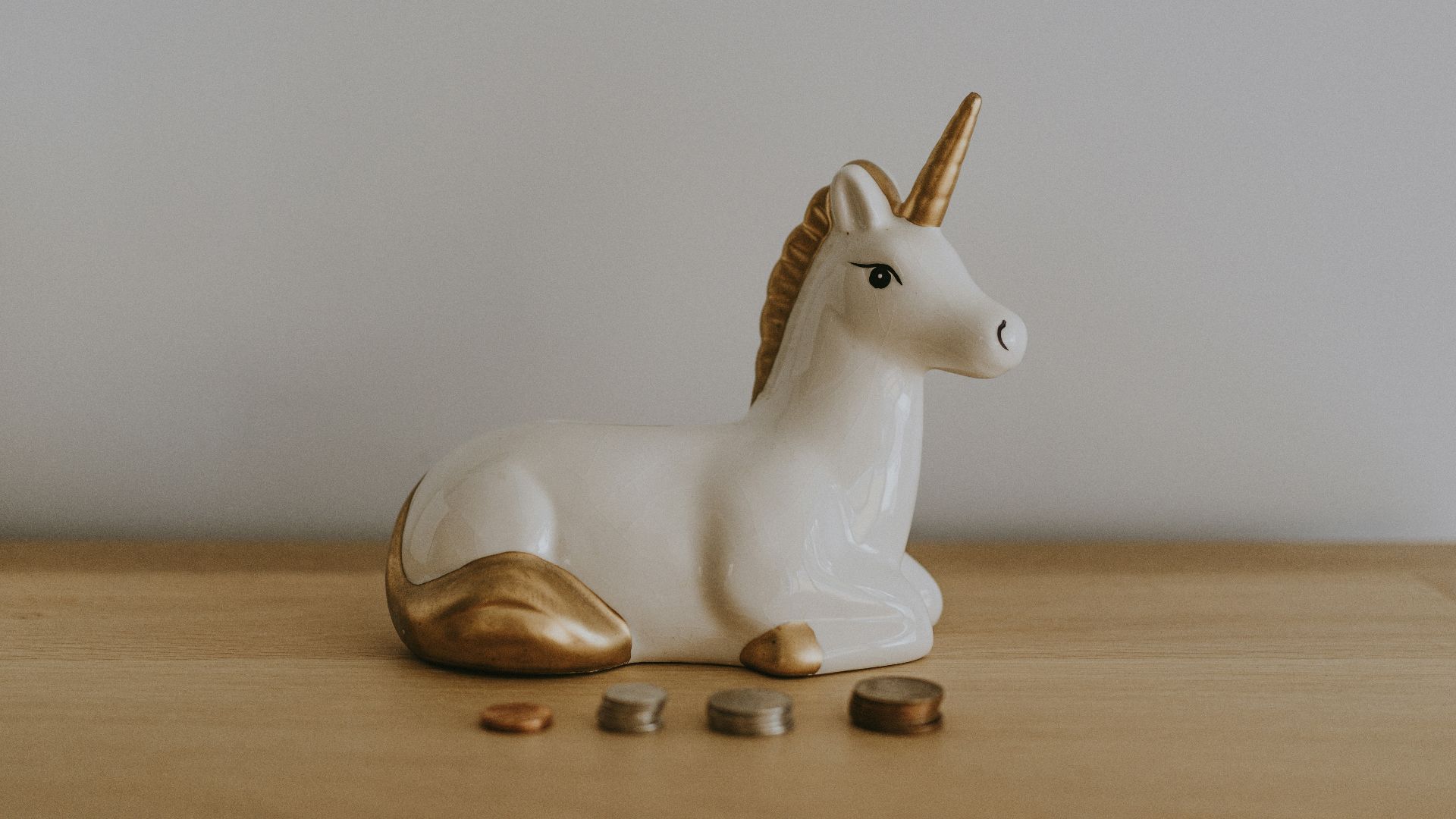 white and gold ceramic unicorn figurine near coins