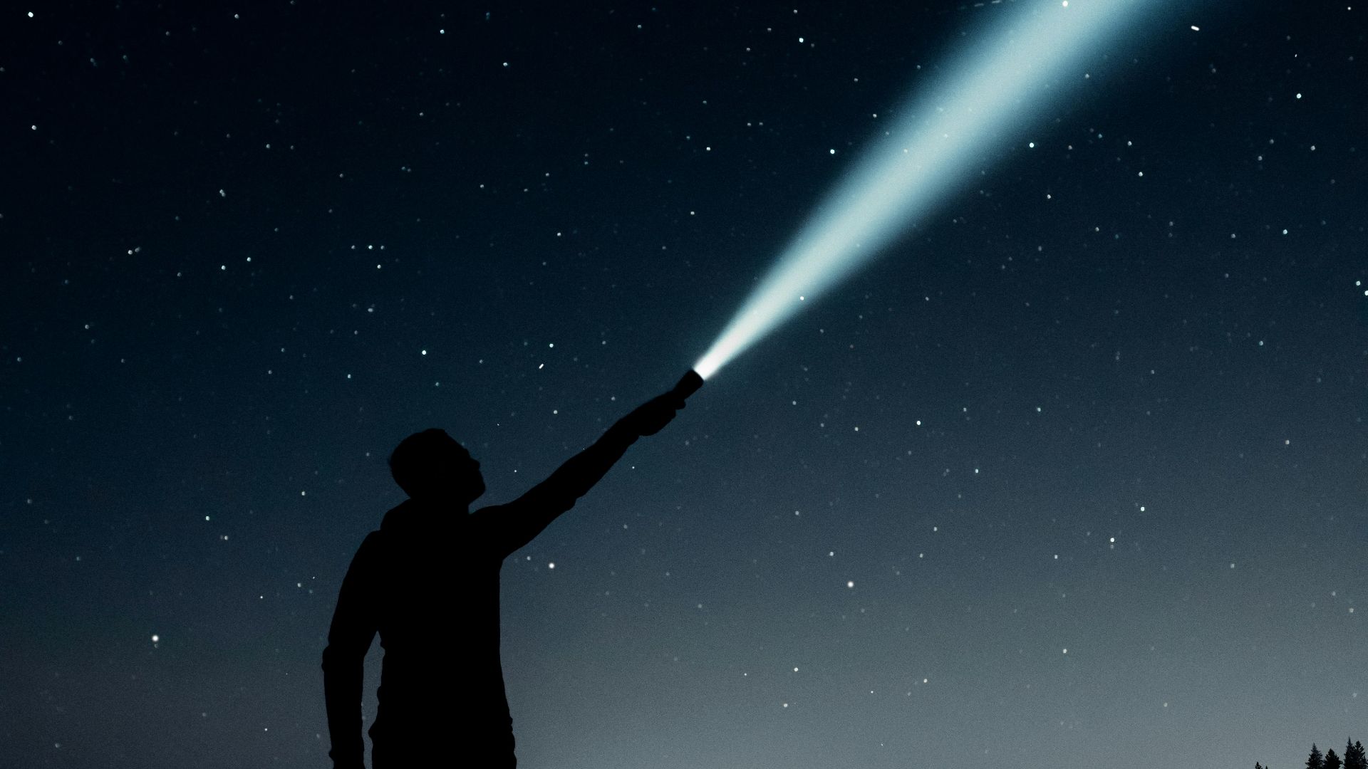 silhouette of man holding flashlight