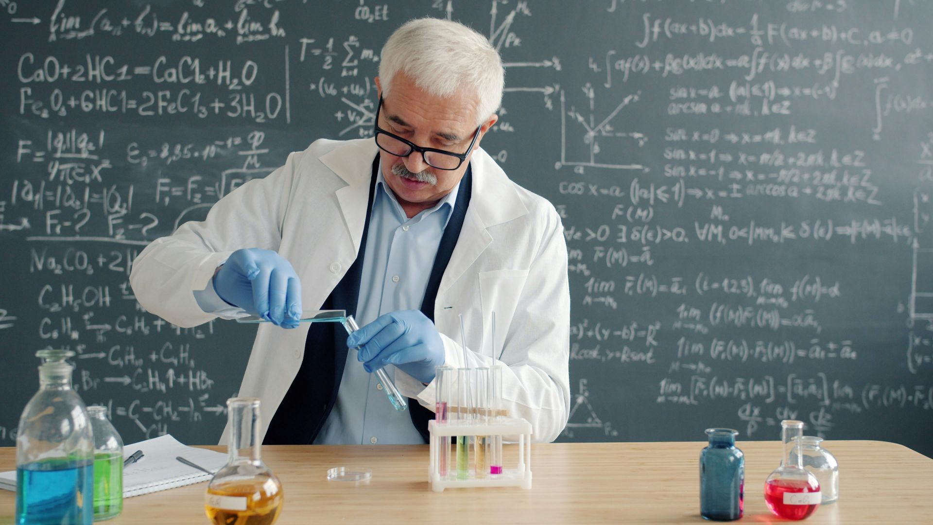 Scientist in lab coat conducts experiment with test tubes.