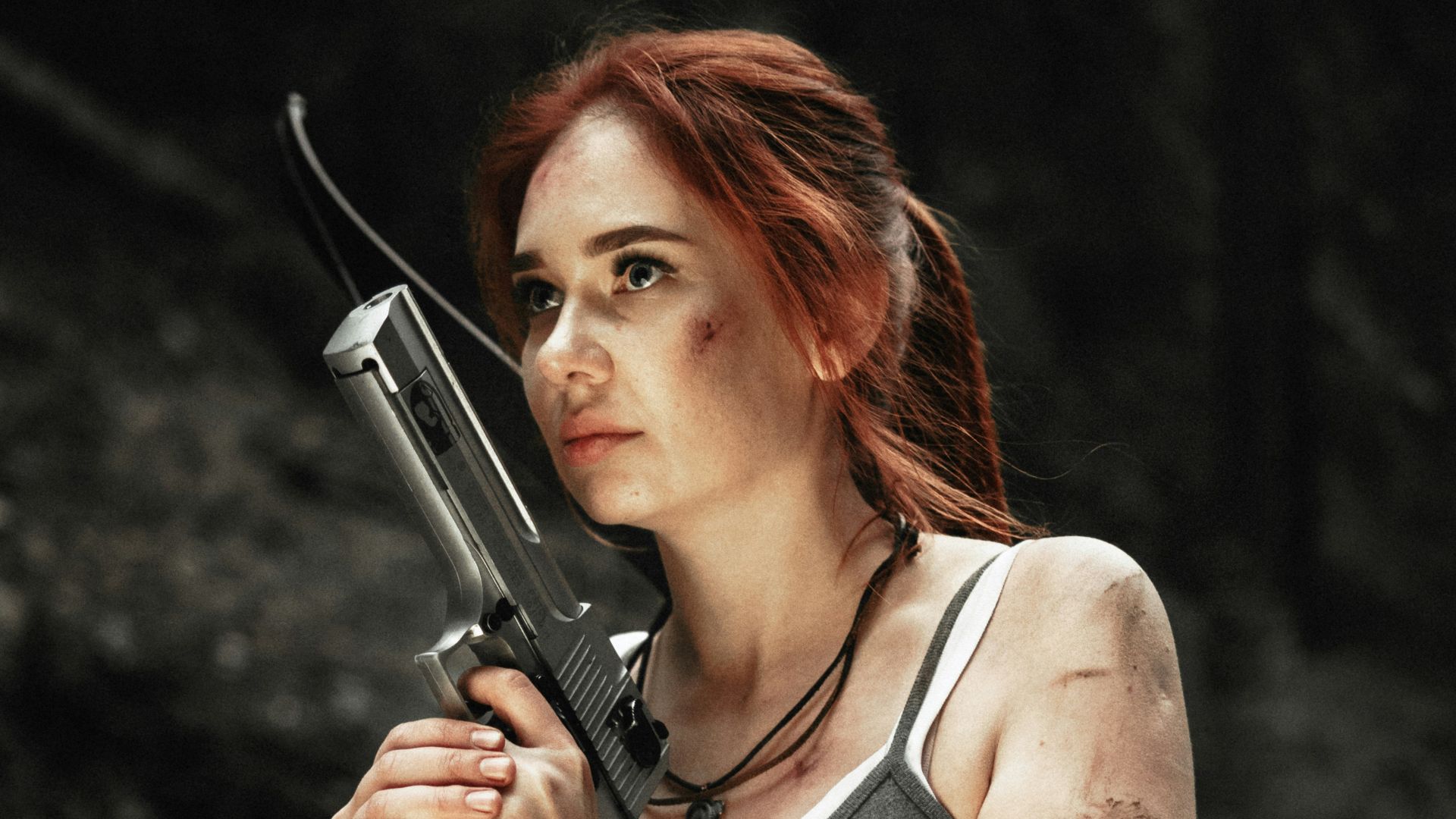 woman wearing gray spaghetti strap blouse holding gray rifle