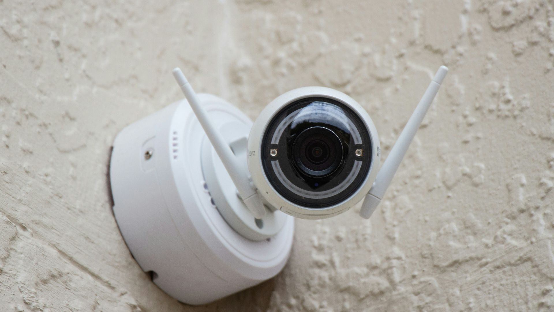 white surveillance camera hanging on wall