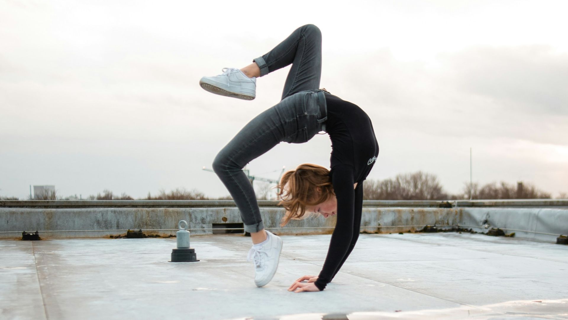 woman doing bridge posts reflecting on water puddle