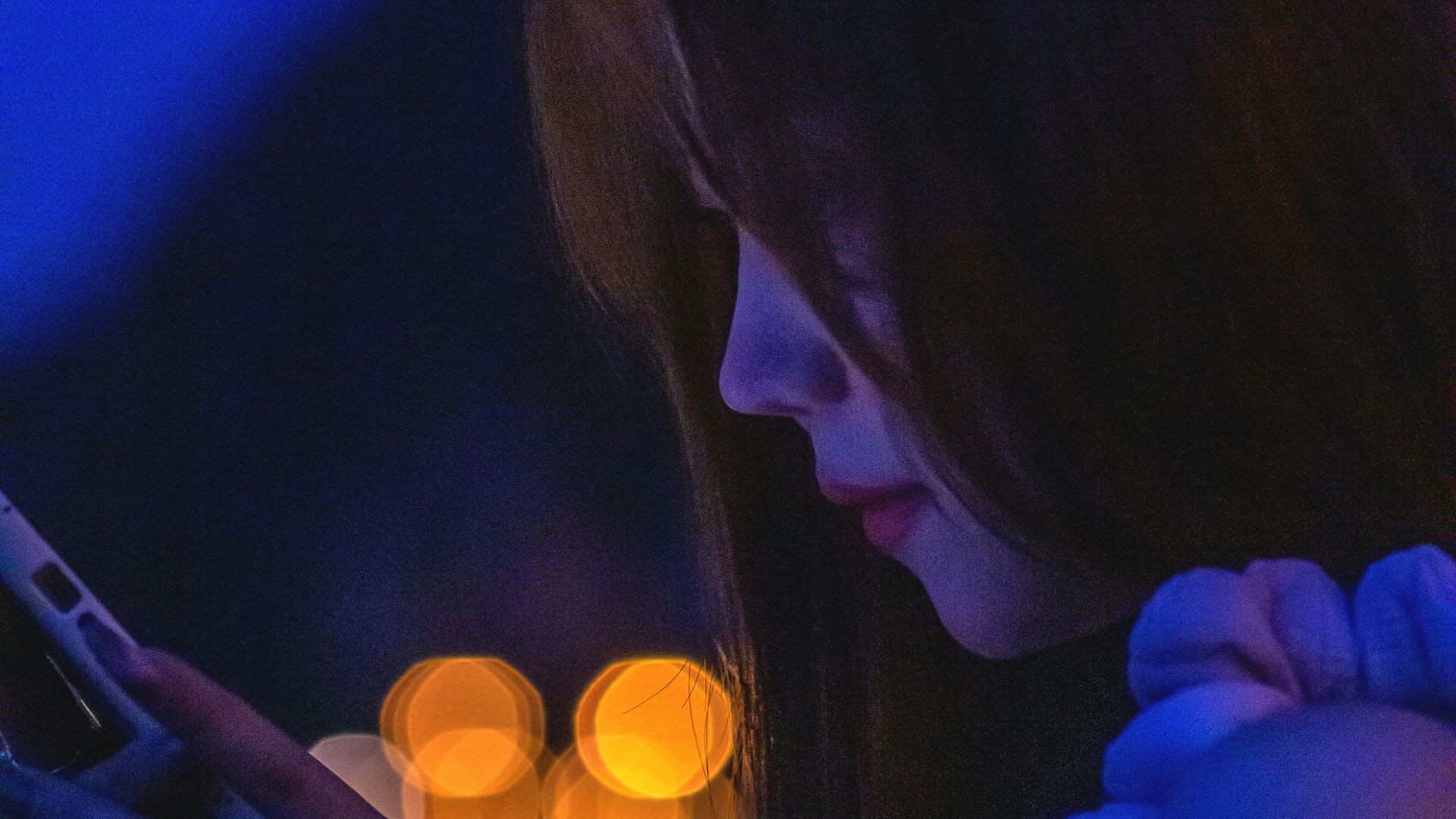 A woman checks her phone, lit by blue light.