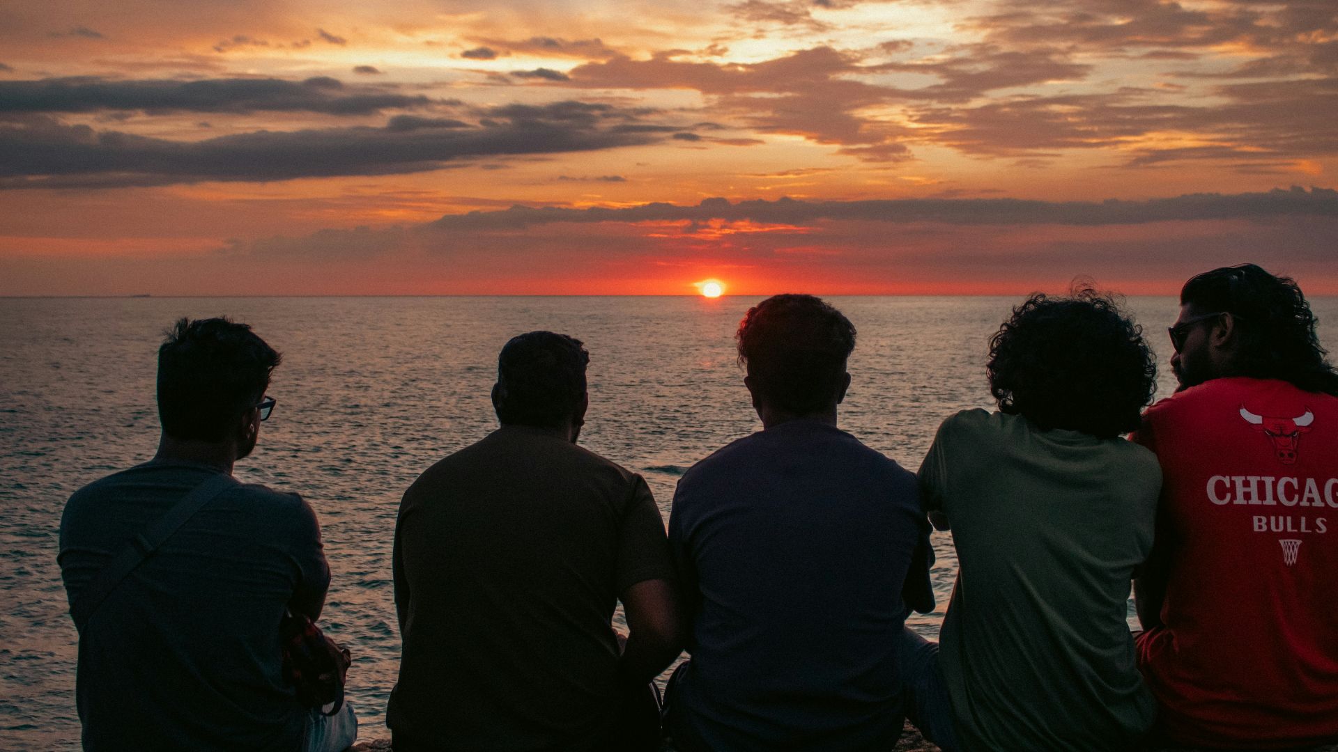 Friends watch the sunset over the ocean.