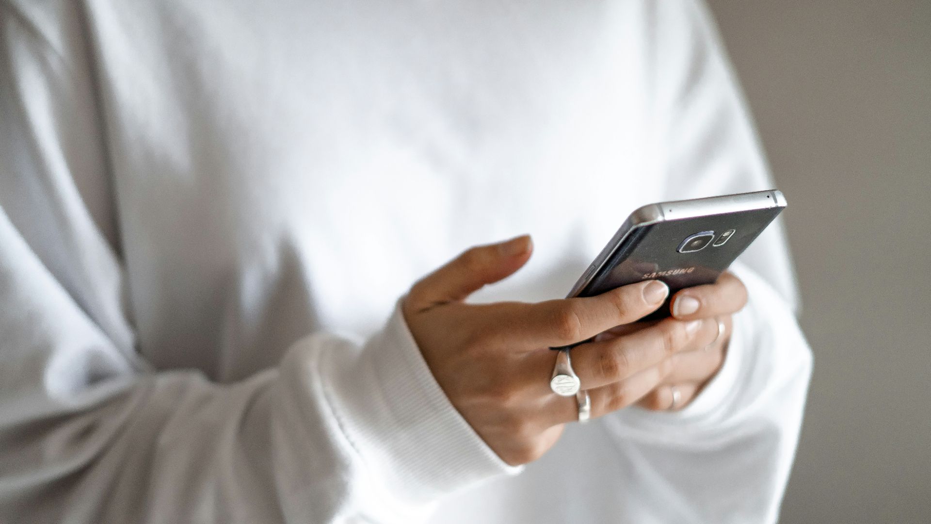 person in white long sleeve shirt holding black smartphone