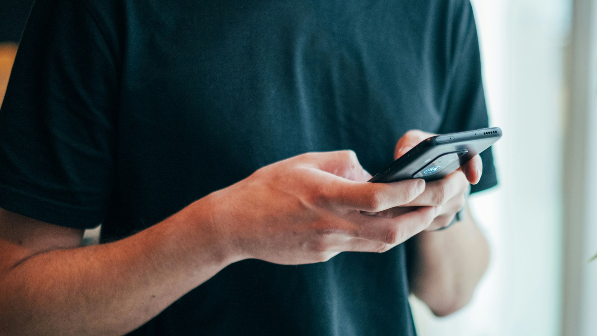 man in black crew-neck top using smartphone