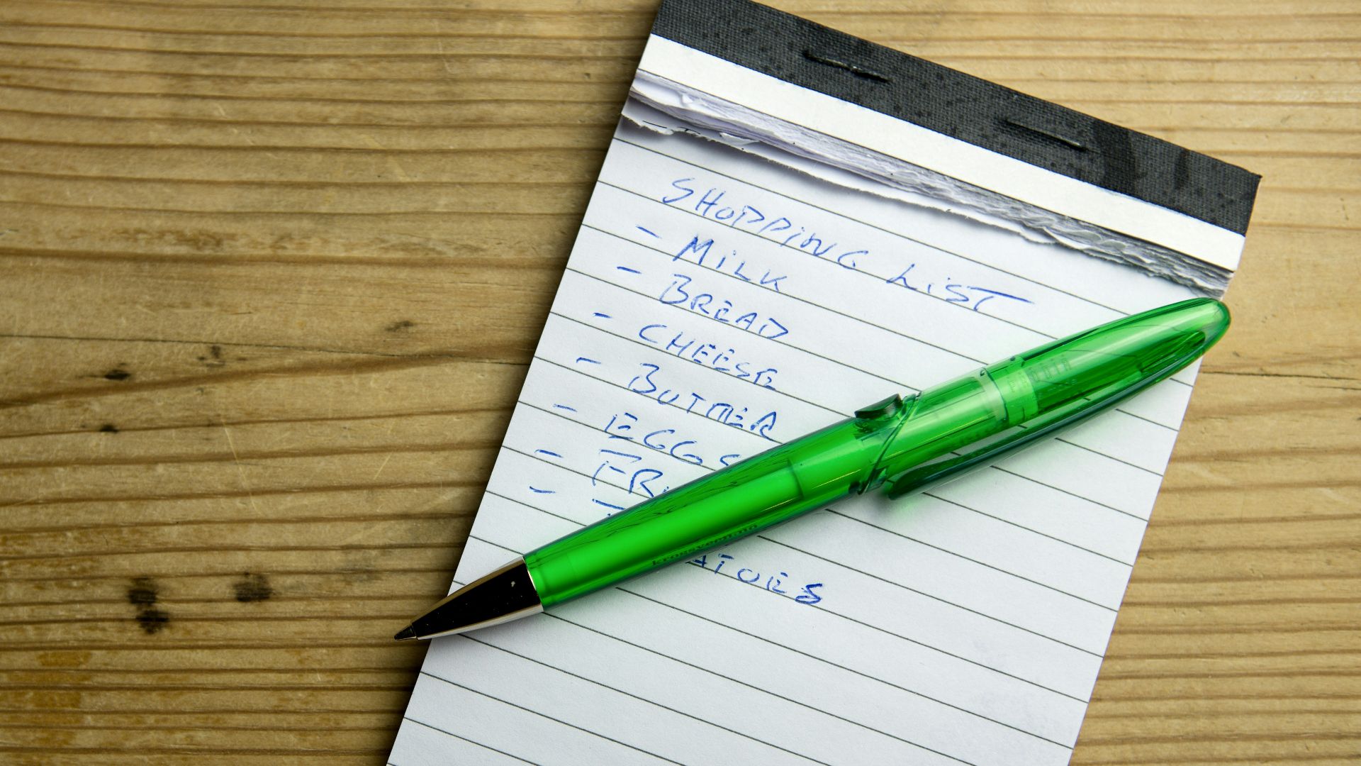 a green pen sitting on top of a piece of paper