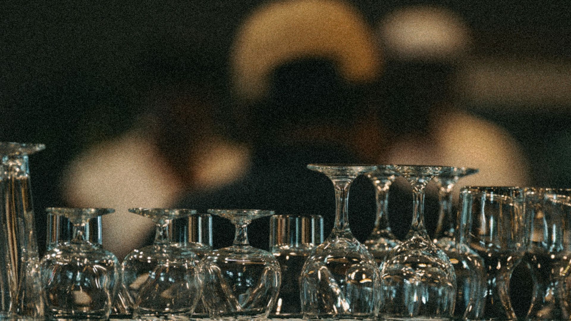 Wine glasses are stacked upside down on a shelf.